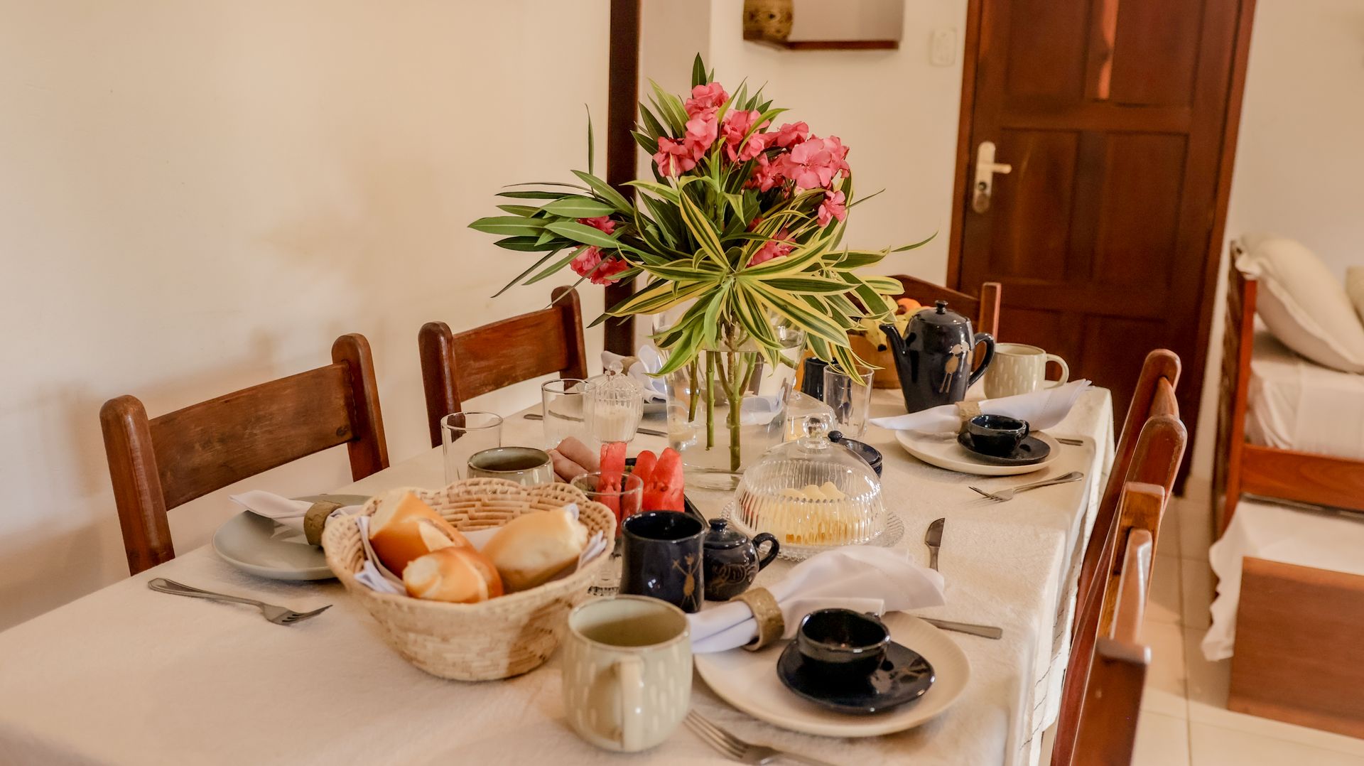 Mesa de jantar posta com comida, flores e louças.