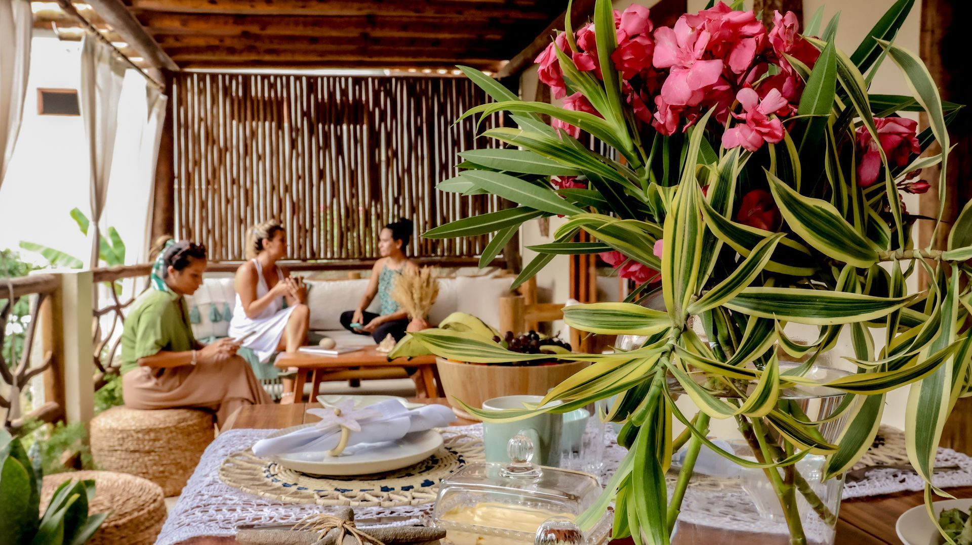 Um grupo de pessoas está sentado em um sofá na varanda com flores em primeiro plano