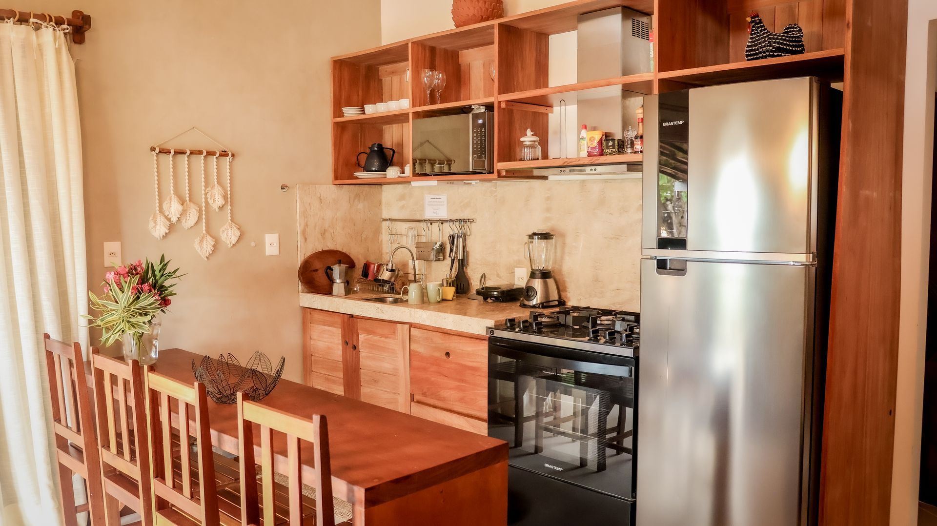 Cozinha com armários de madeira, geladeira de aço inoxidável e mesa de jantar com cadeiras.