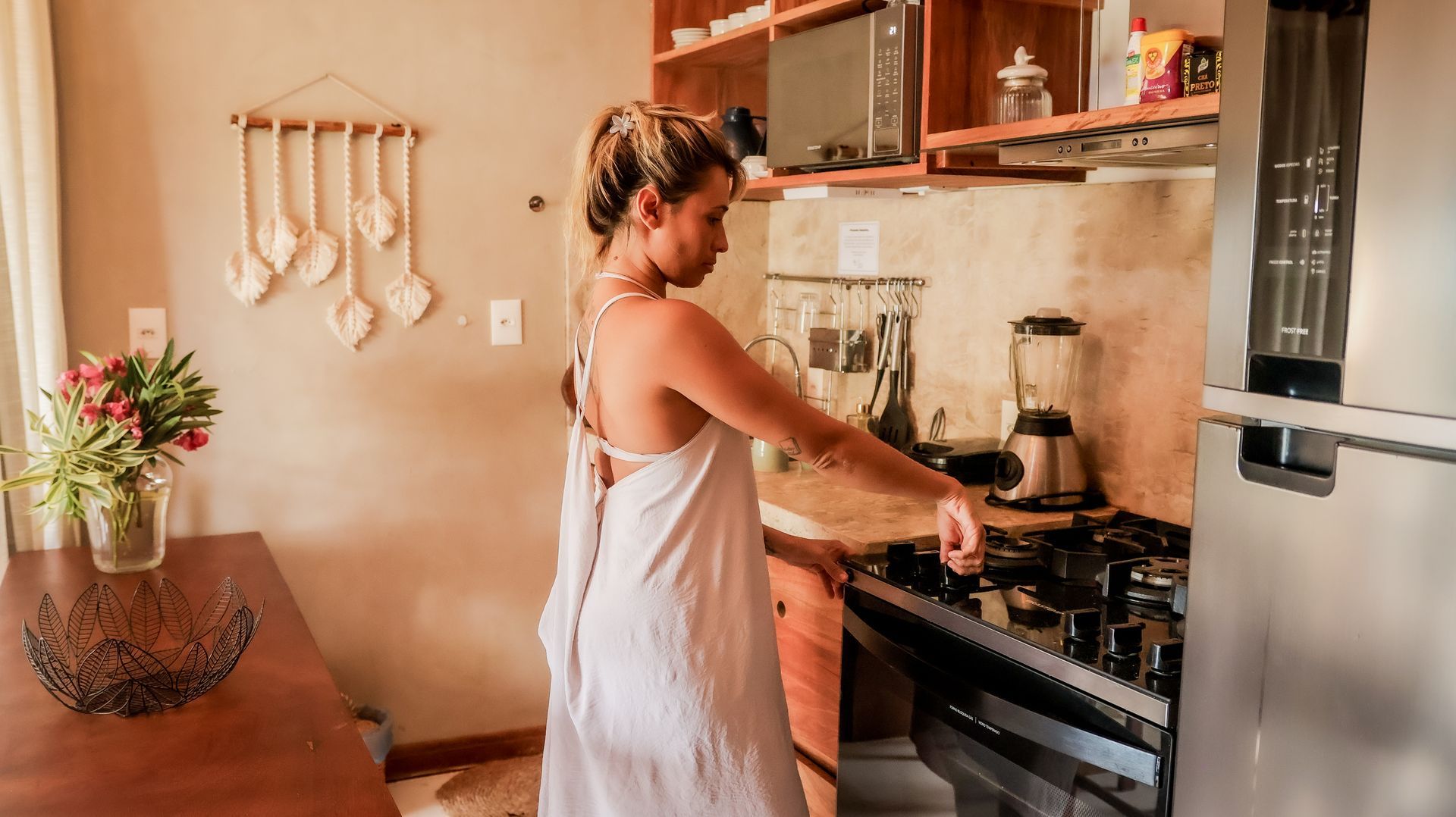 Uma mulher de vestido branco está cozinhando em uma cozinha