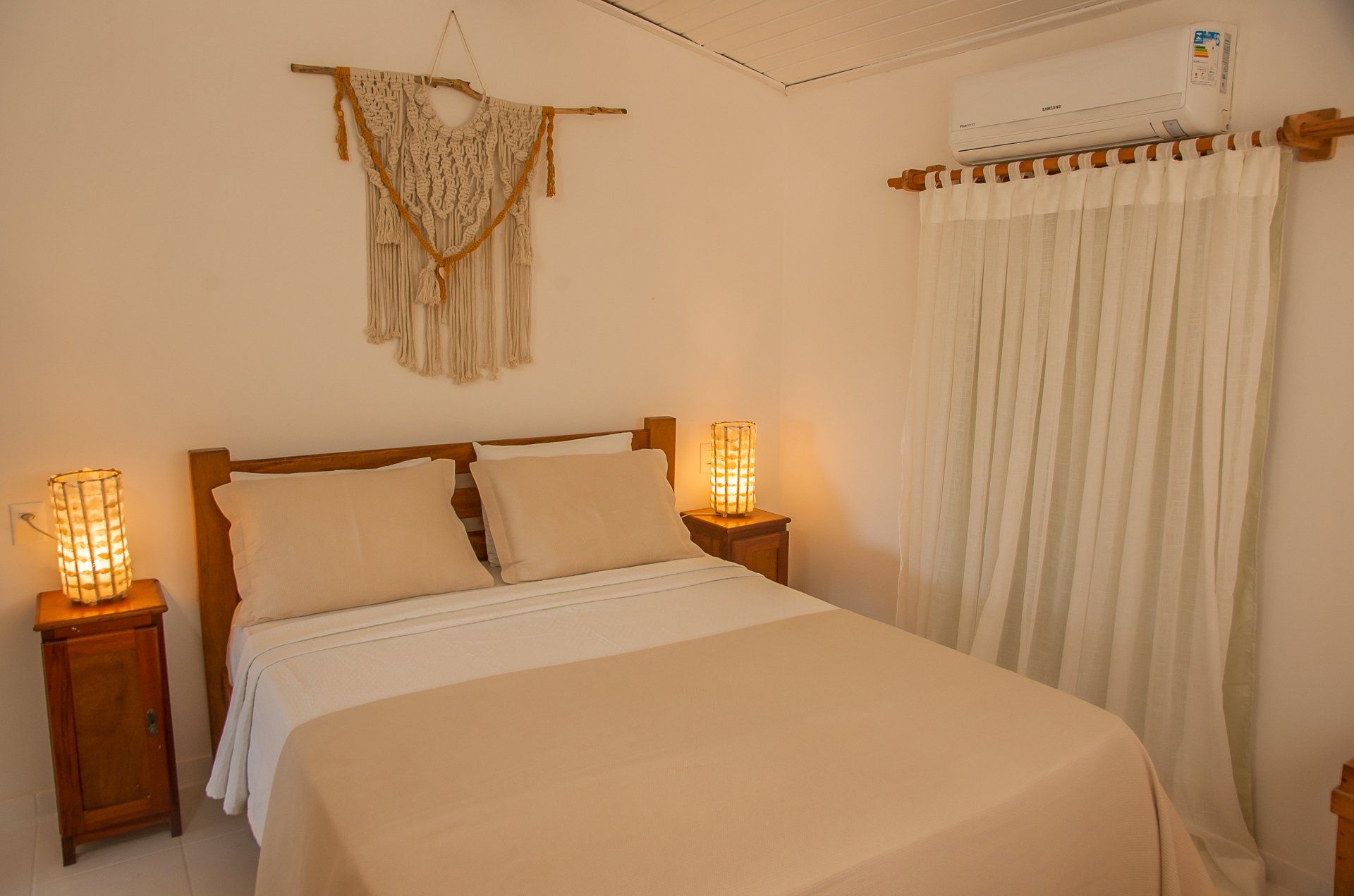 Um quarto com uma cama, mesas de cabeceira, abajures e cortinas.