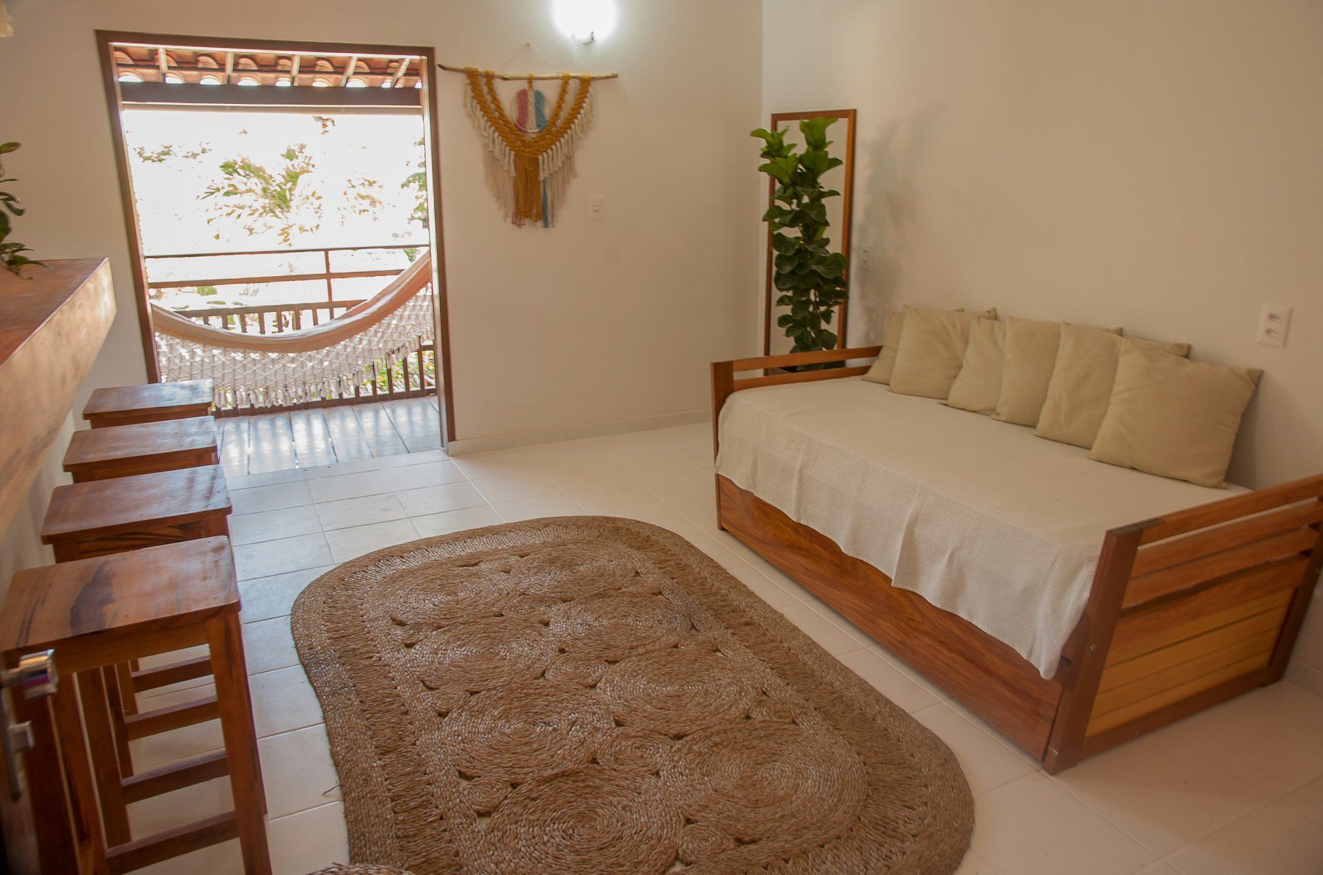 Uma sala de estar com um sofá, tapete, bancos e uma rede.