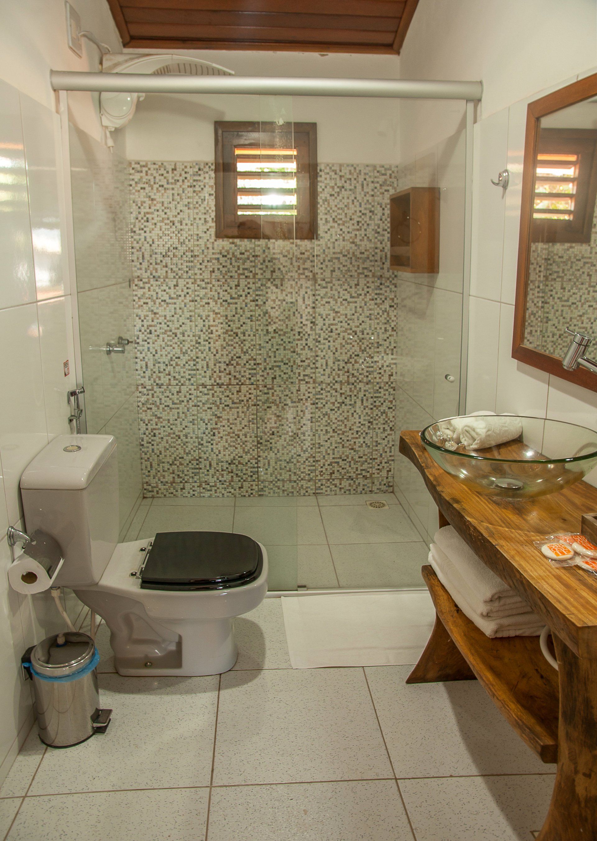 Um banheiro com vaso sanitário, pia, espelho e chuveiro.