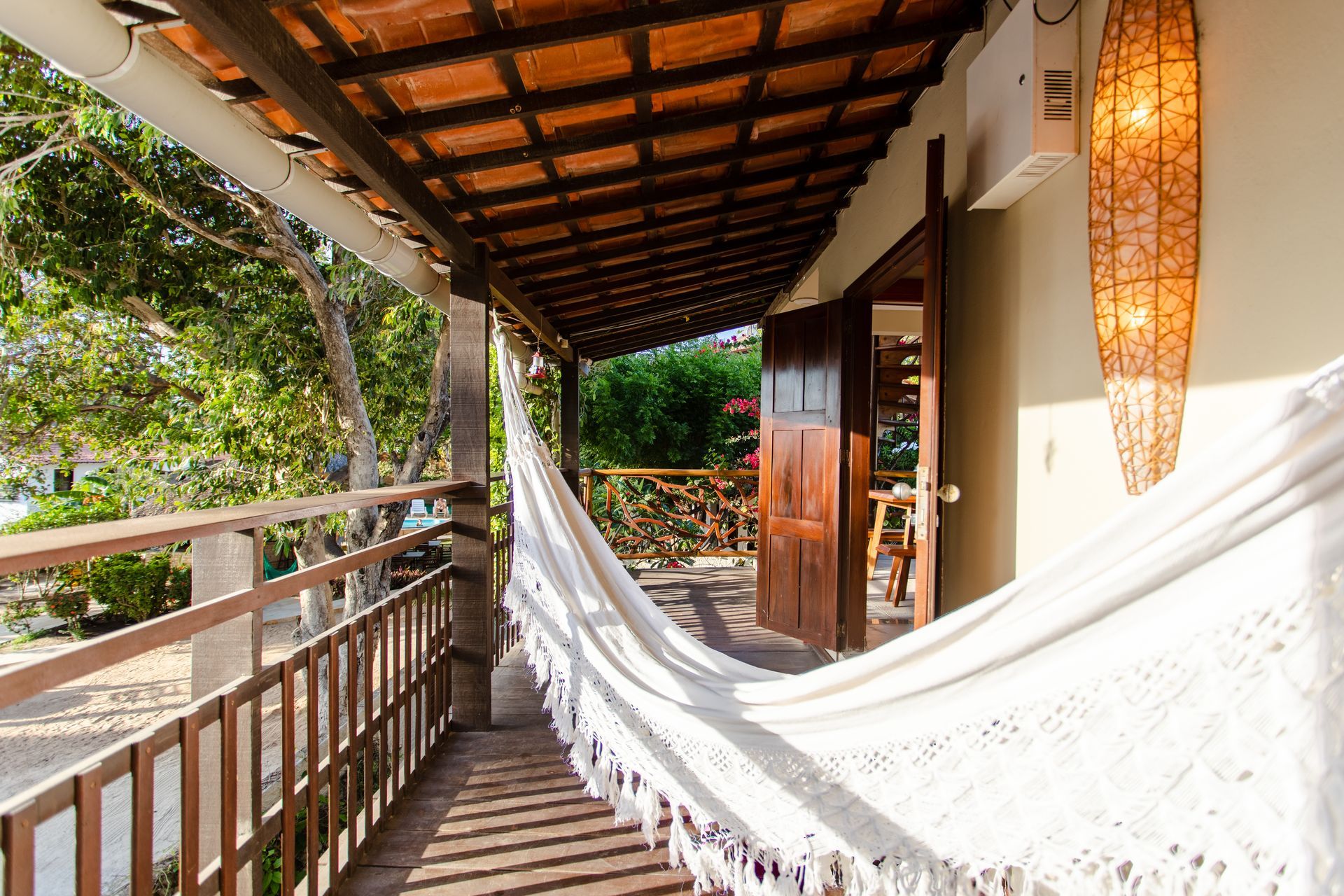 Uma rede está pendurada em uma varanda com um corrimão de madeira