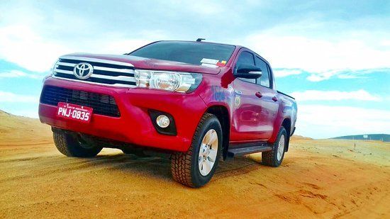Um caminhão vermelho está estacionado no meio de um campo de terra.