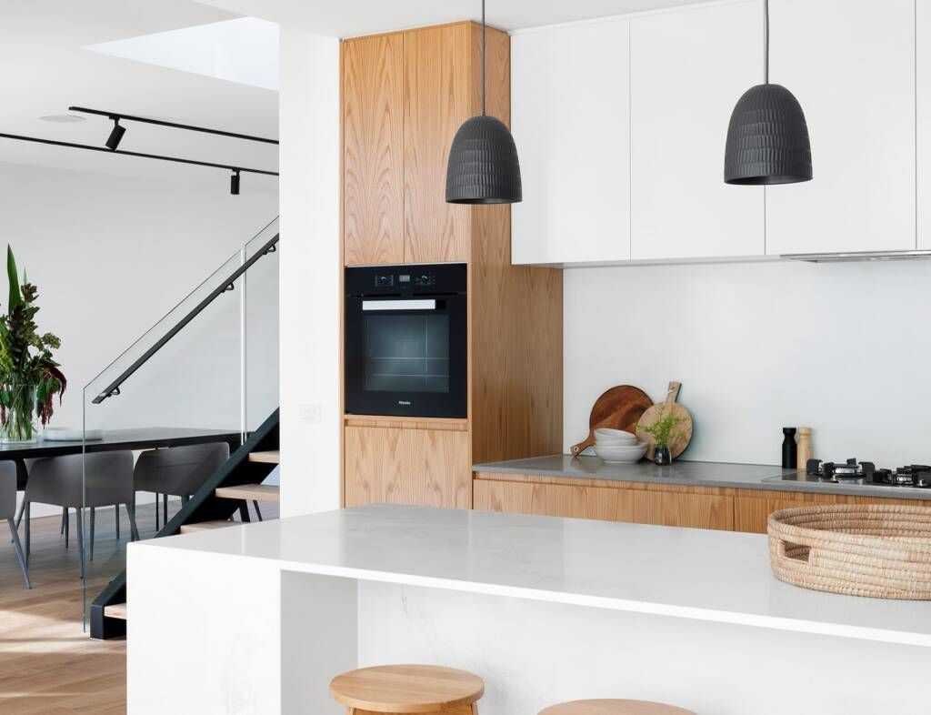 A kitchen with white cabinets and wooden cabinets and a black oven.
