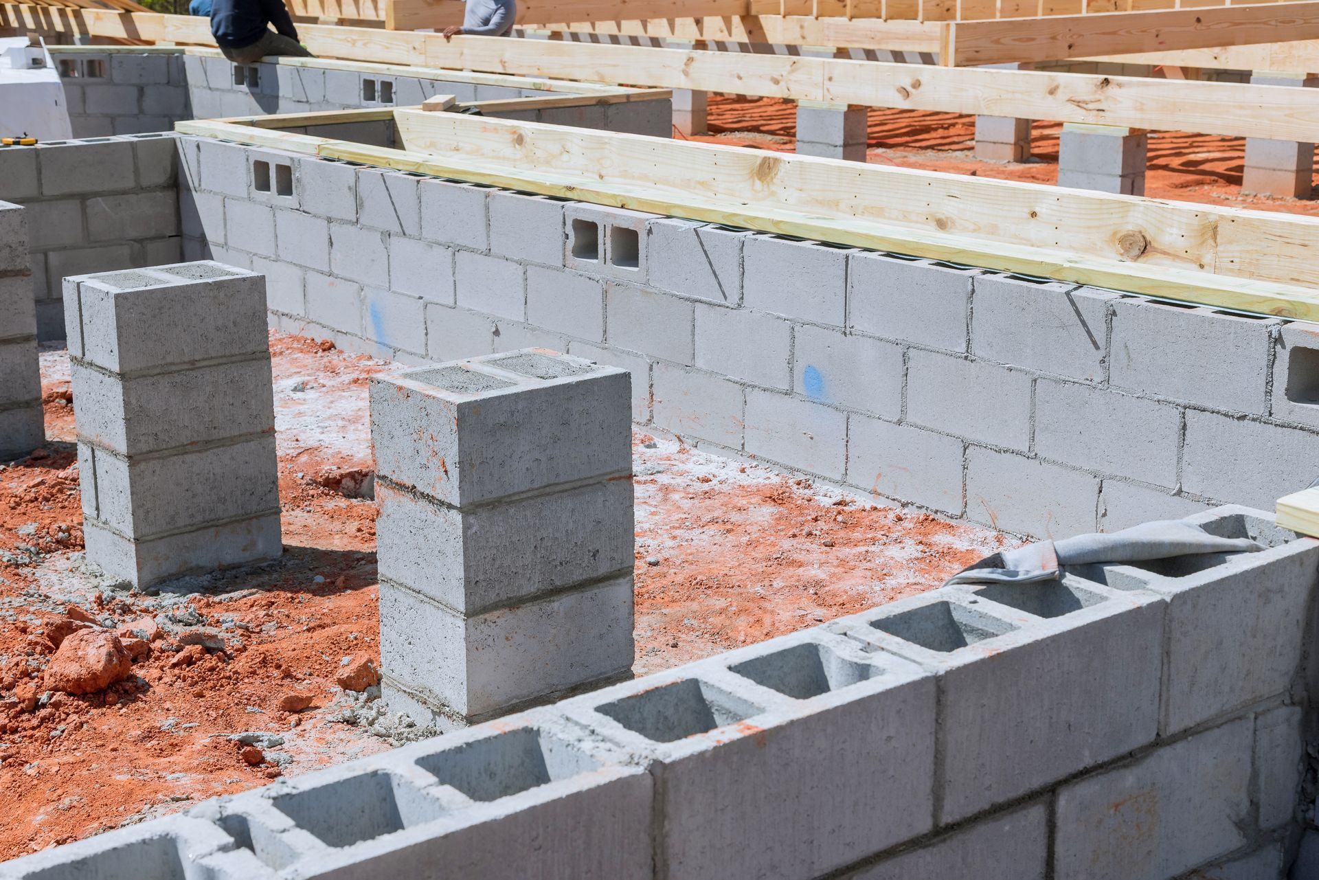 Foundation of a building under construction, made of gray cinder blocks and wooden beams.