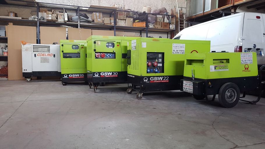 Una fila di generatori industriali verde lime e bianchi parcheggiati all'interno di un magazzino.