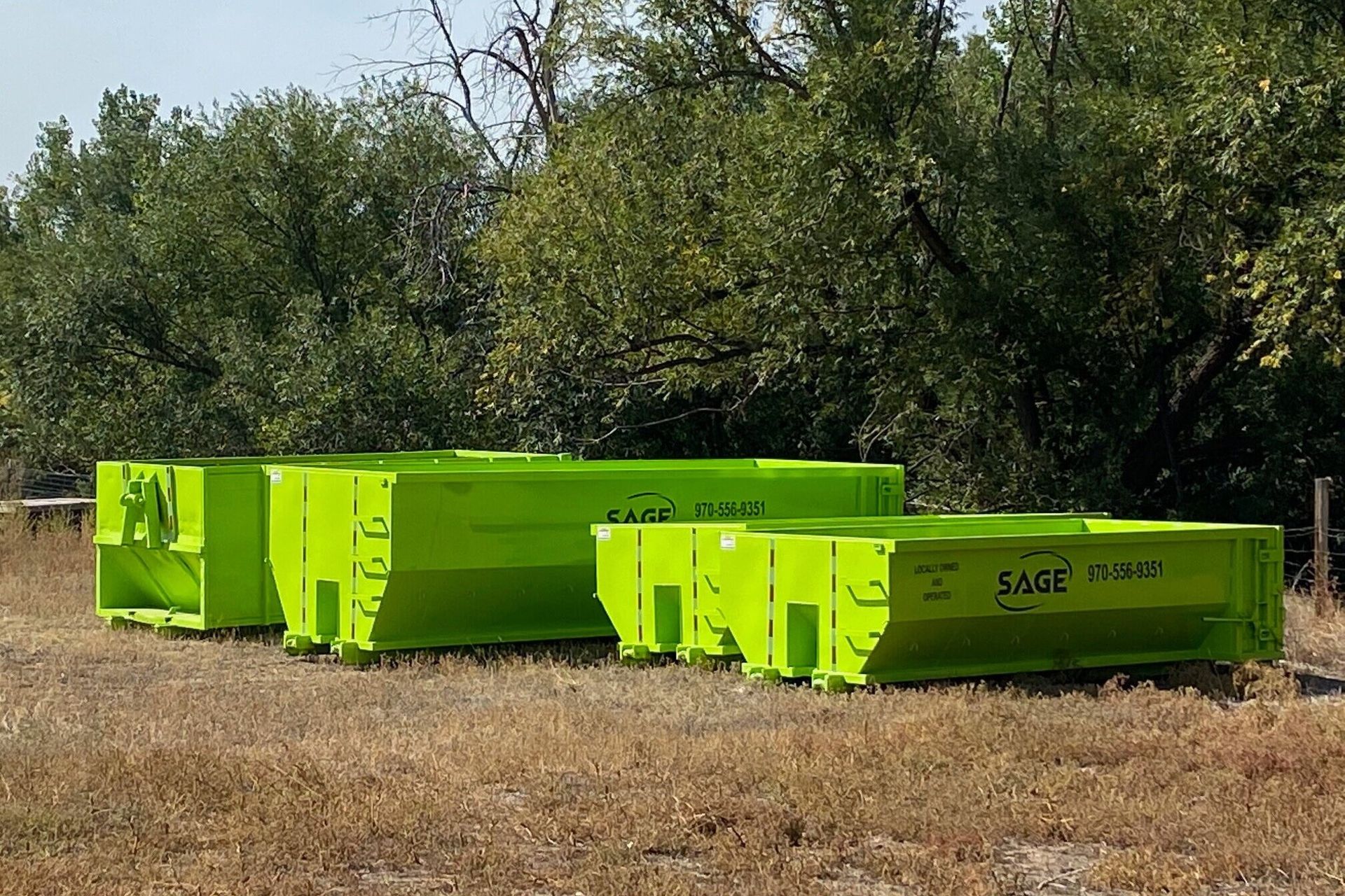 A row of green dumpsters with the word sage on them