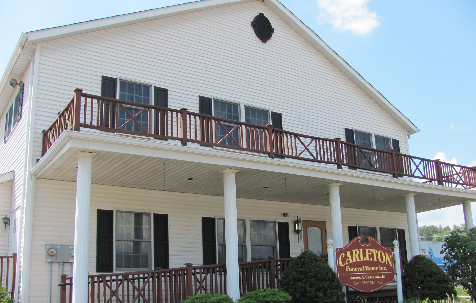 The front door of a house with a porch and plants in front of it.