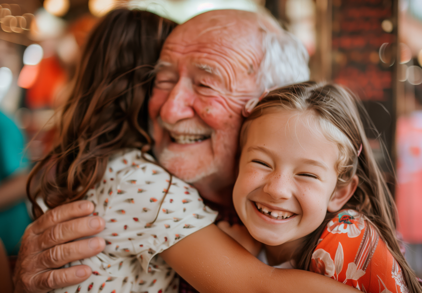 Abuelo sonriente abrazado por dos nietas sonrientes.