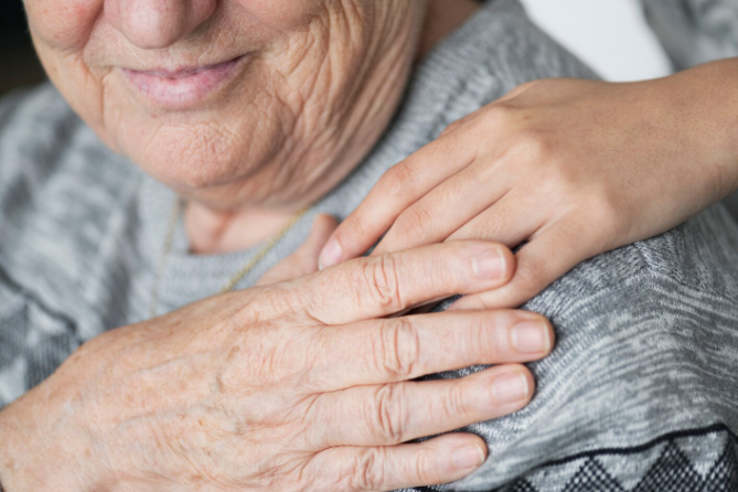 Una persona mayor toma la mano de otra y le ofrece consuelo y apoyo.