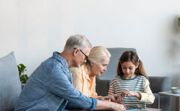 Abuelos y nieta mirando algo juntos, posiblemente un juego.
