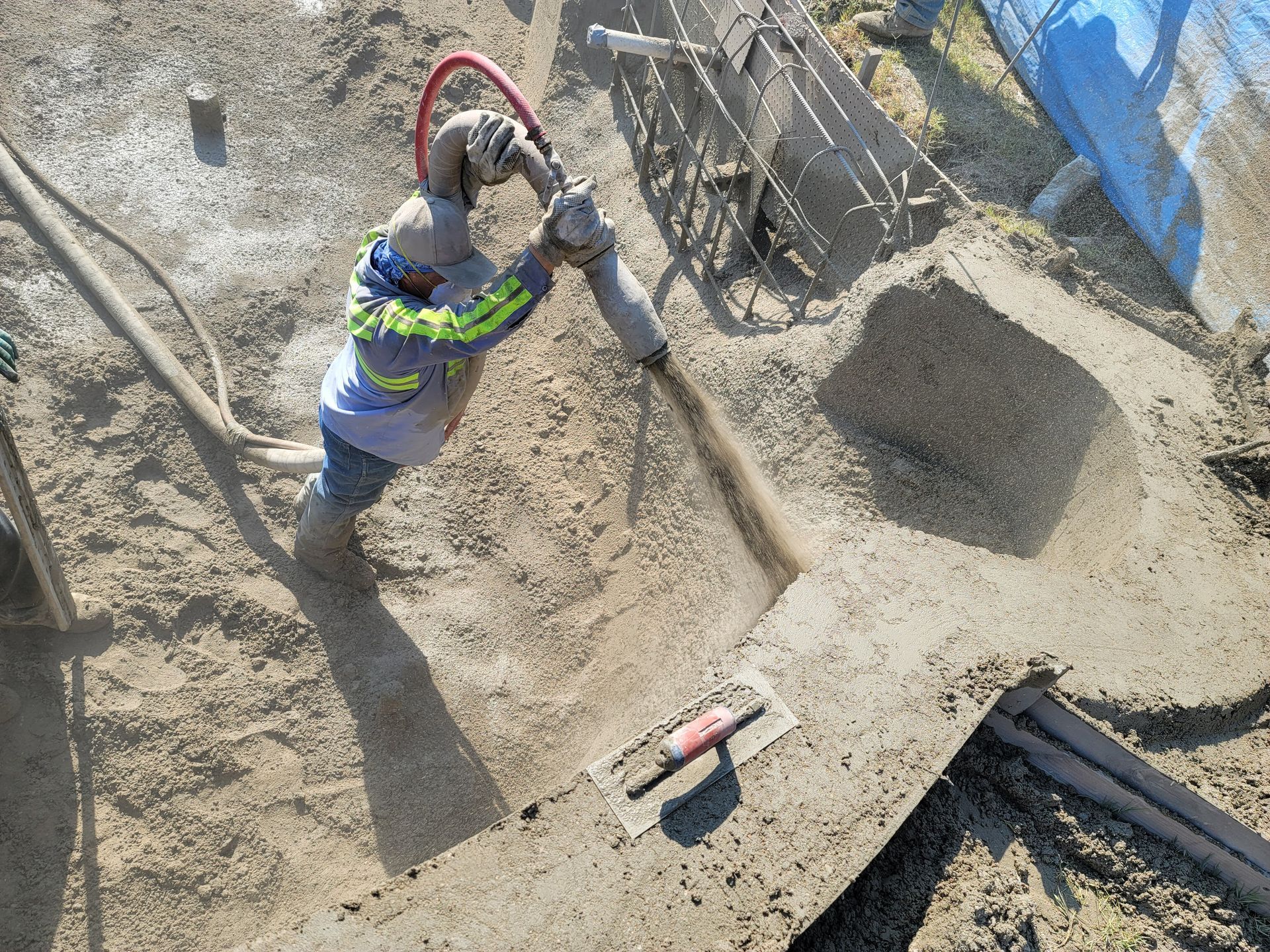A man is using a hose to pump concrete into a hole.
