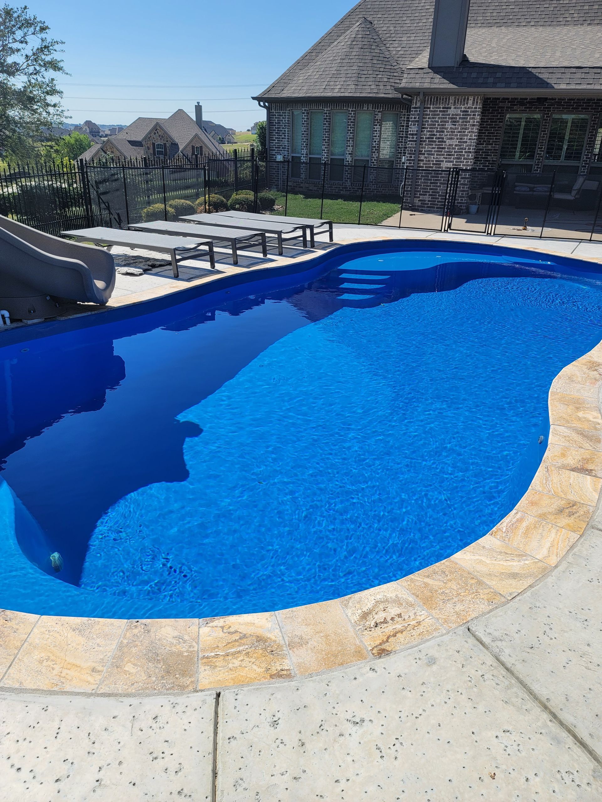 A large blue swimming pool with a house in the background