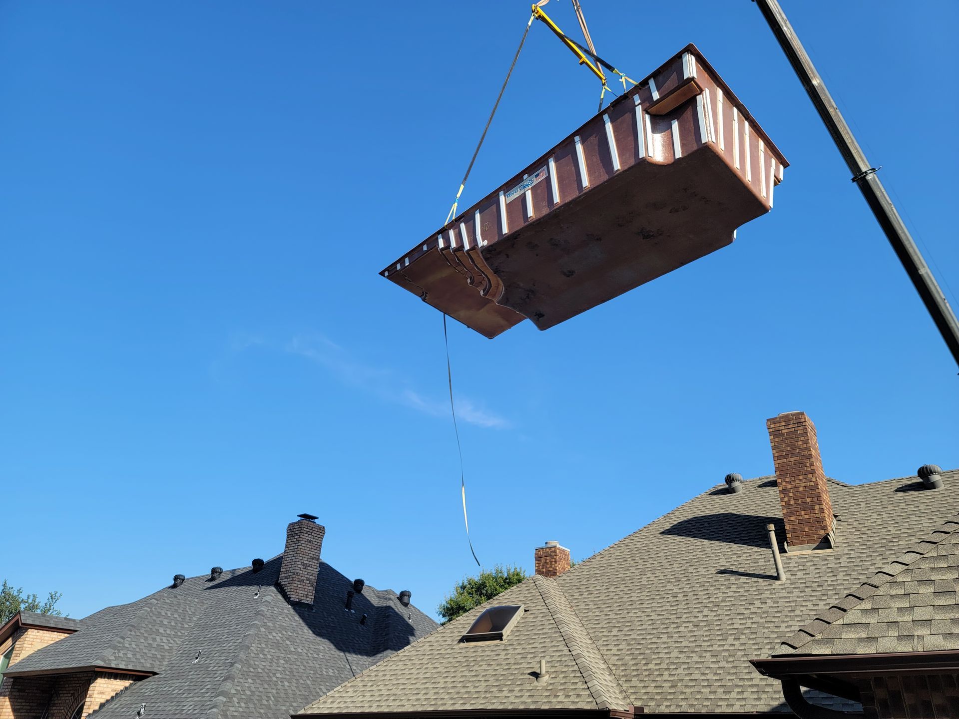 A large piece of wood is being lifted into the air by a crane