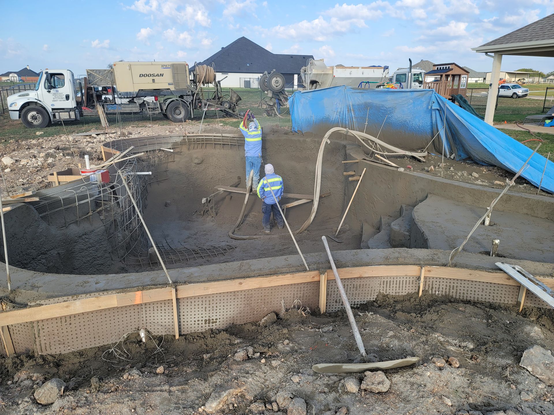 A group of construction workers are working on a swimming pool.