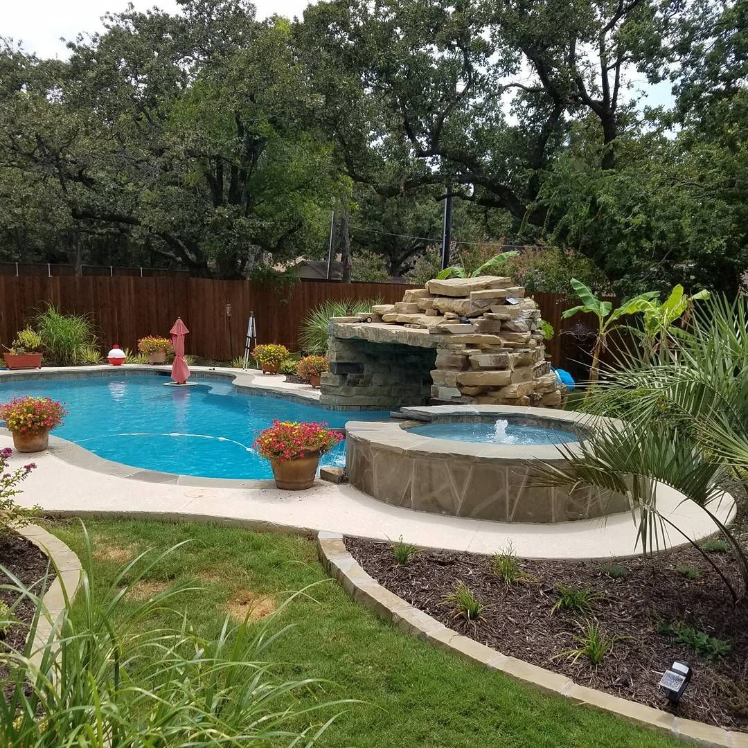 A large swimming pool with a waterfall in the backyard.