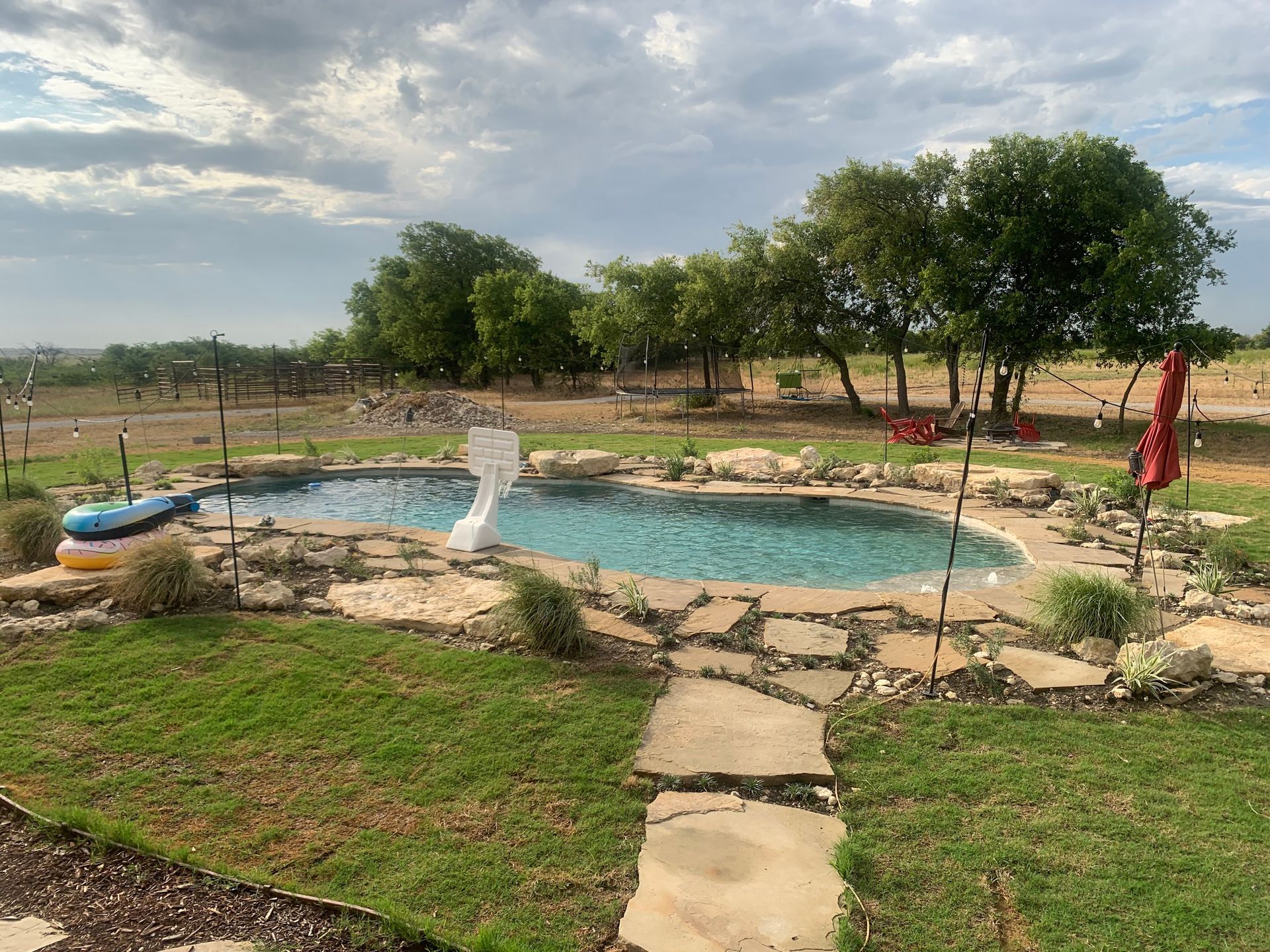 There is a large swimming pool in the middle of a lush green field.