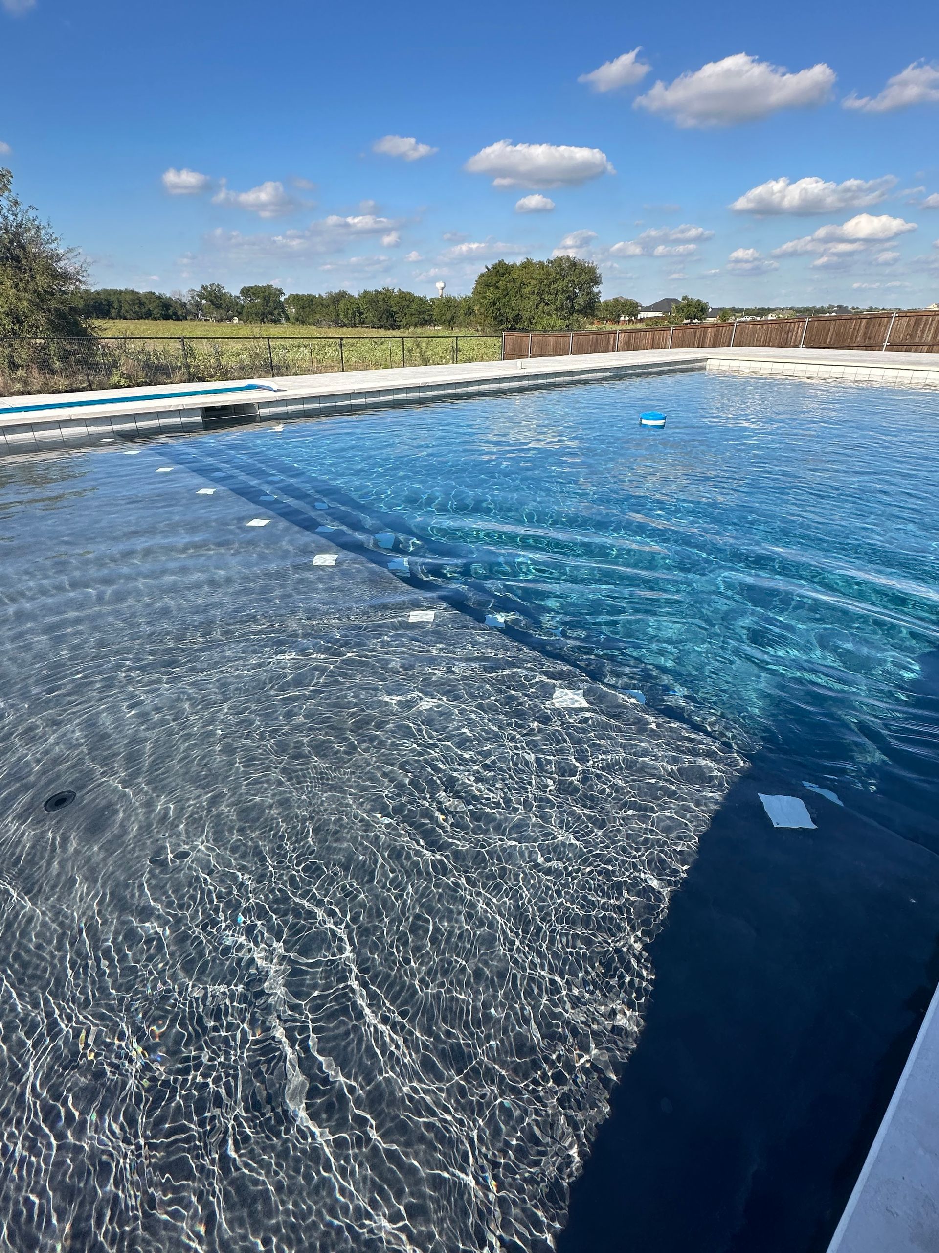 A large swimming pool with a blue sky and clouds in the background.