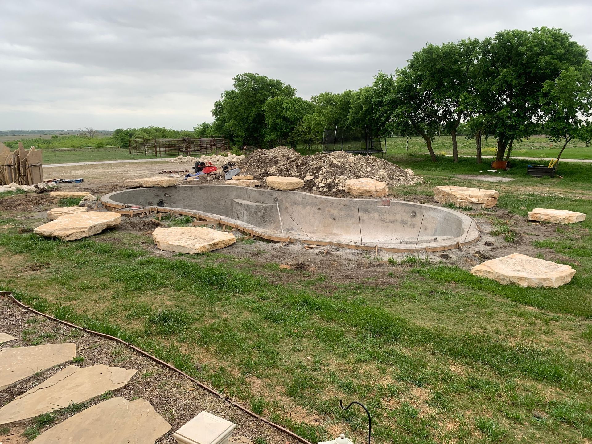 A large pool is being built in the middle of a lush green field.