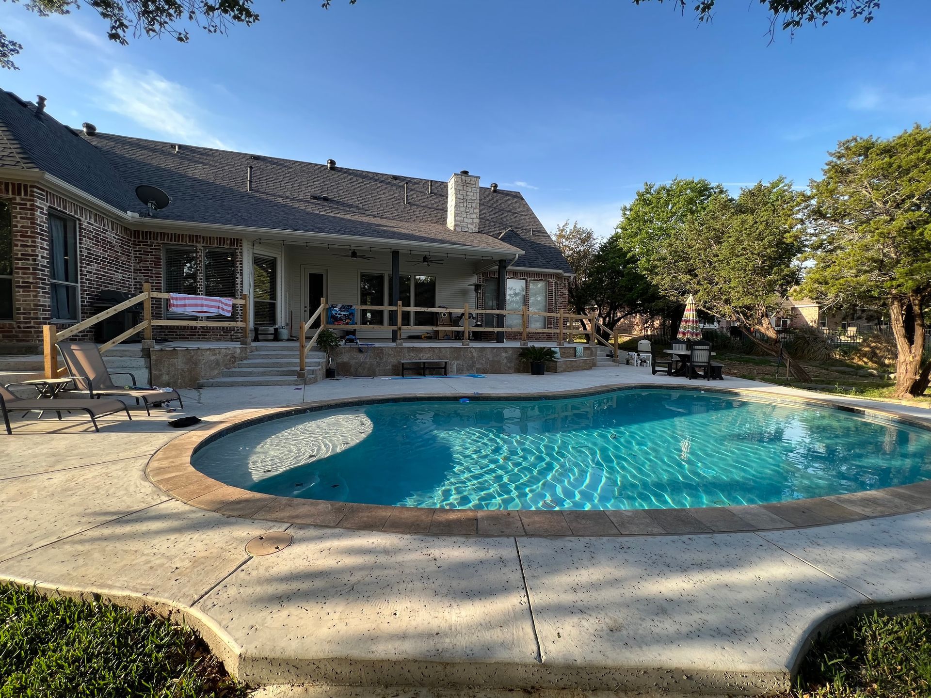 A large swimming pool is in the backyard of a house.