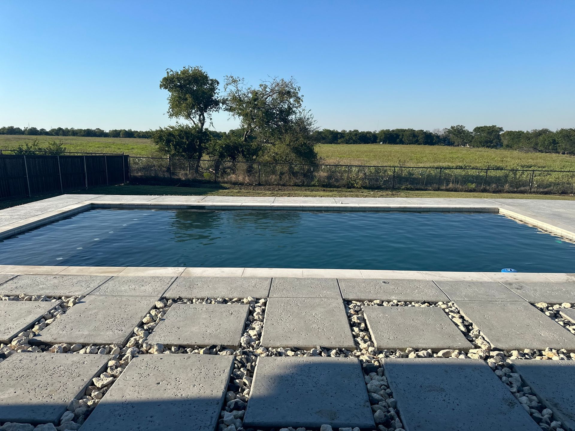 A large swimming pool is surrounded by bricks and gravel
