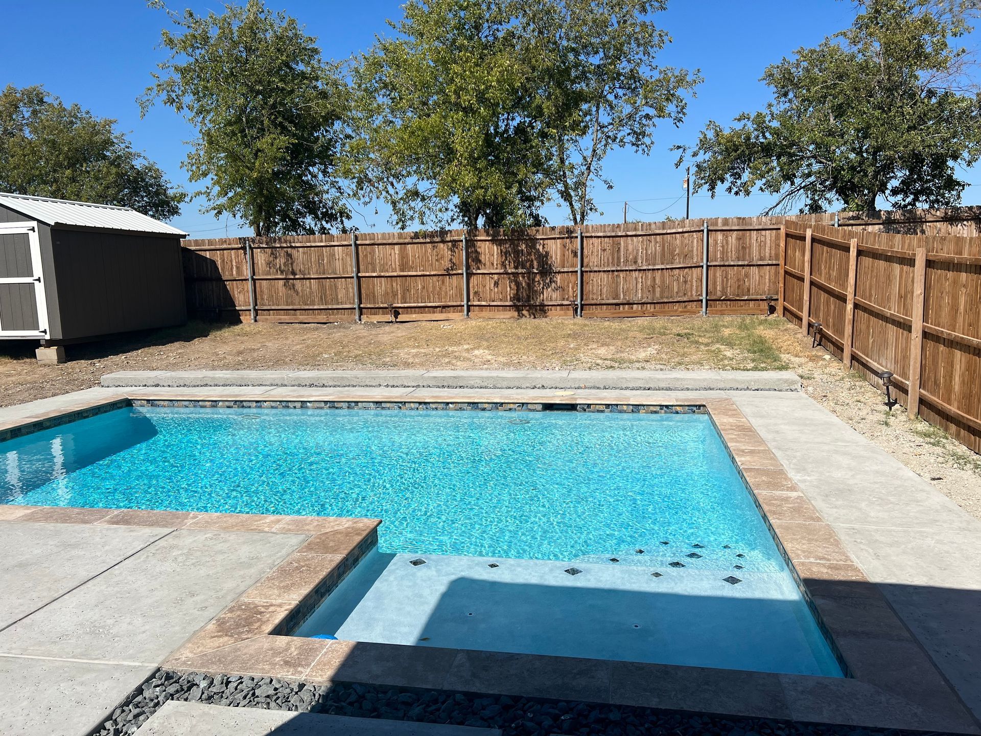 A man in a blue shirt is working on a swimming pool.