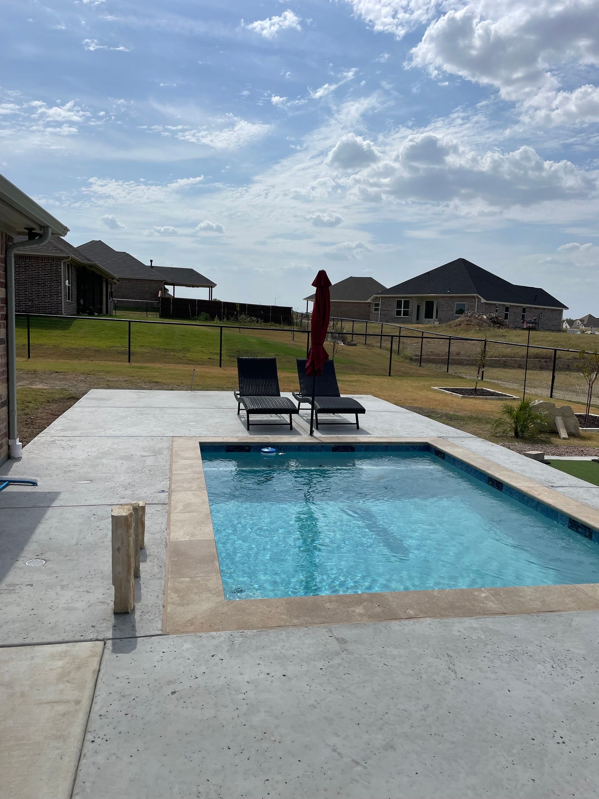 A chair is sitting on a wooden deck next to a swimming pool.