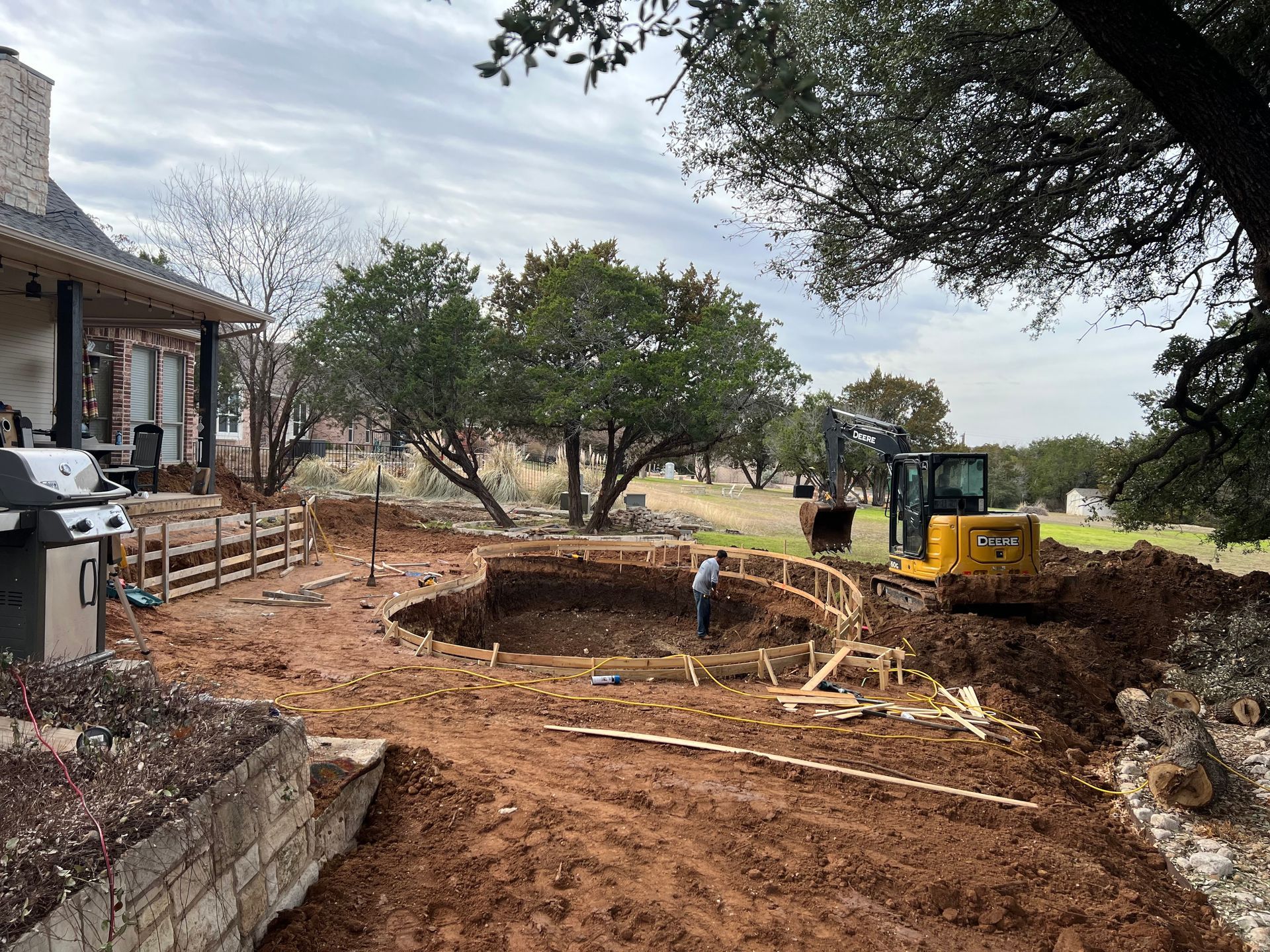 A man is digging a hole in the dirt in front of a house.