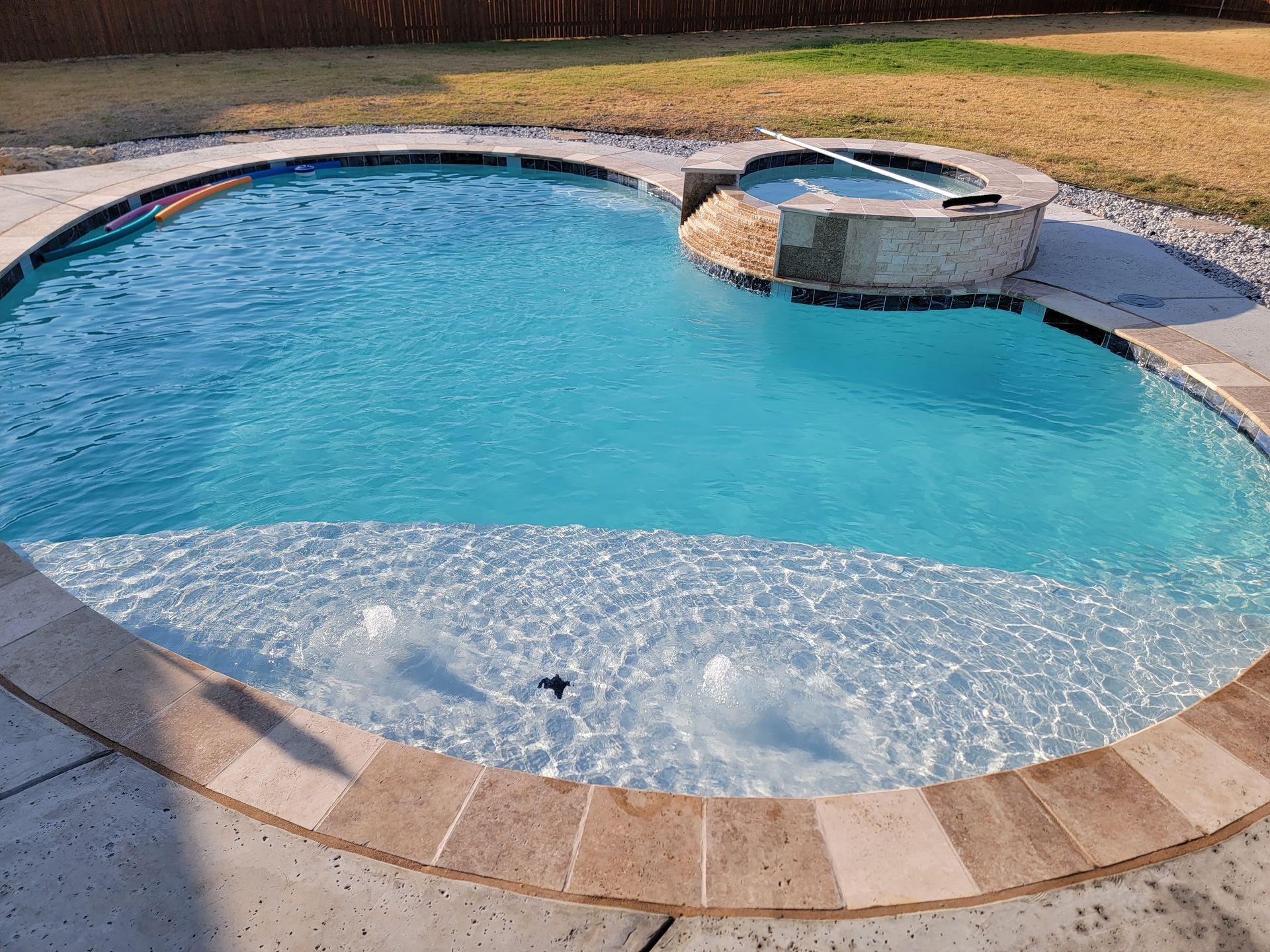 A large swimming pool with a hot tub in the middle of it.