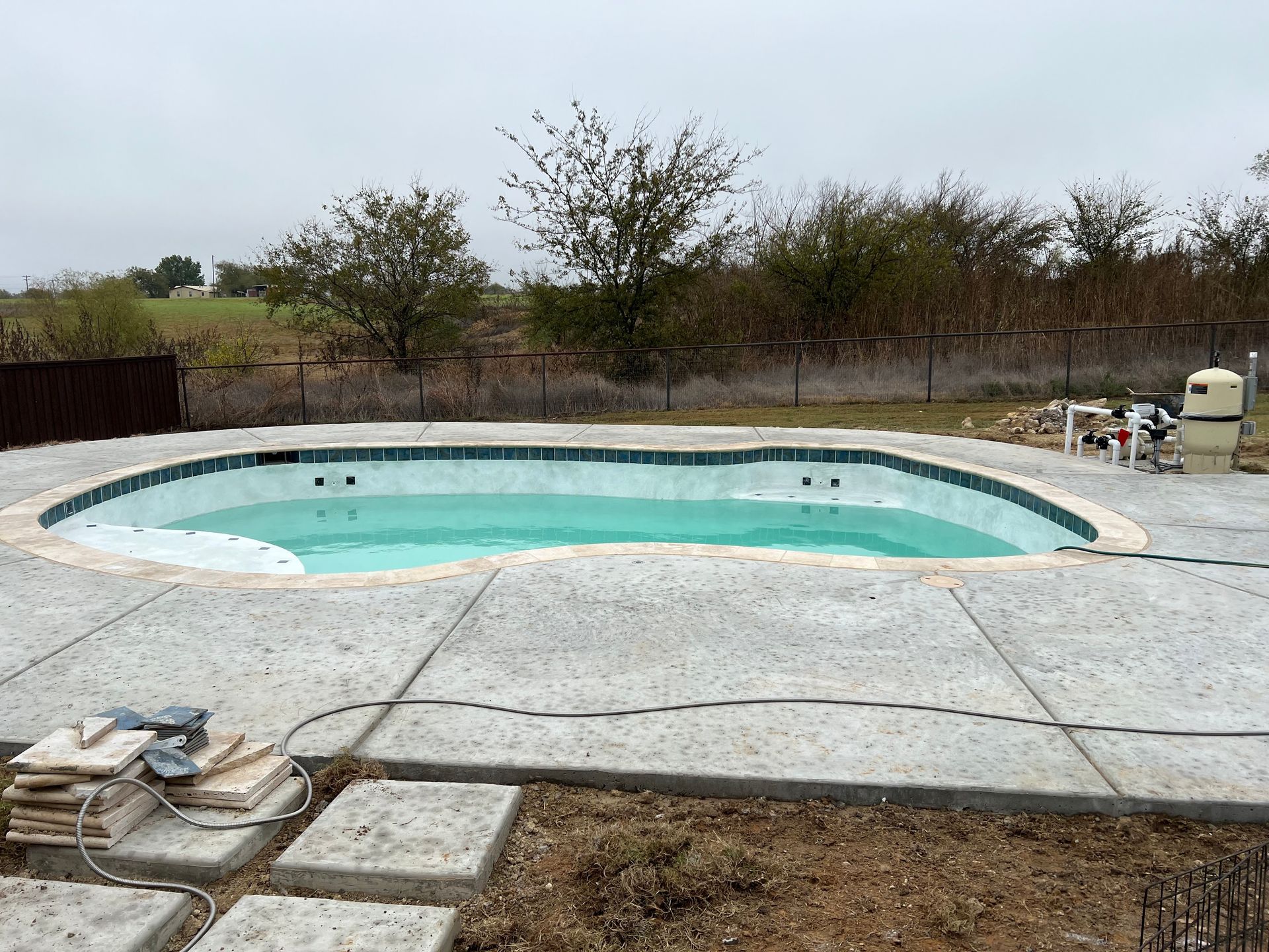 A large swimming pool is being built in a backyard.