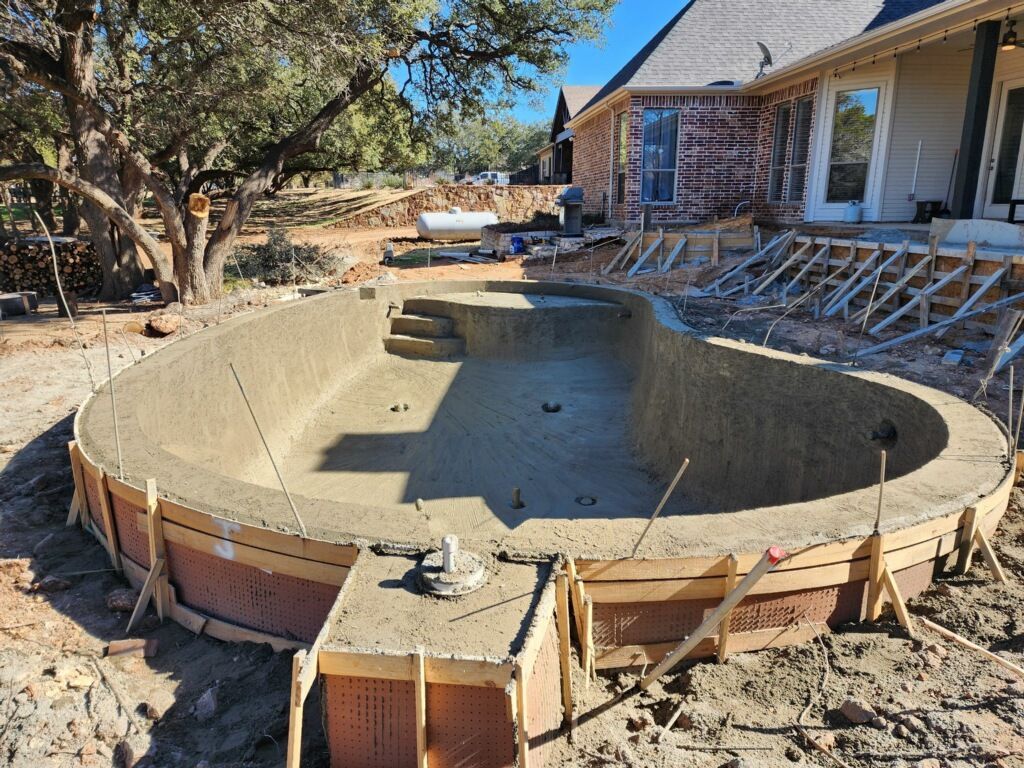 A large swimming pool is being built in front of a house.