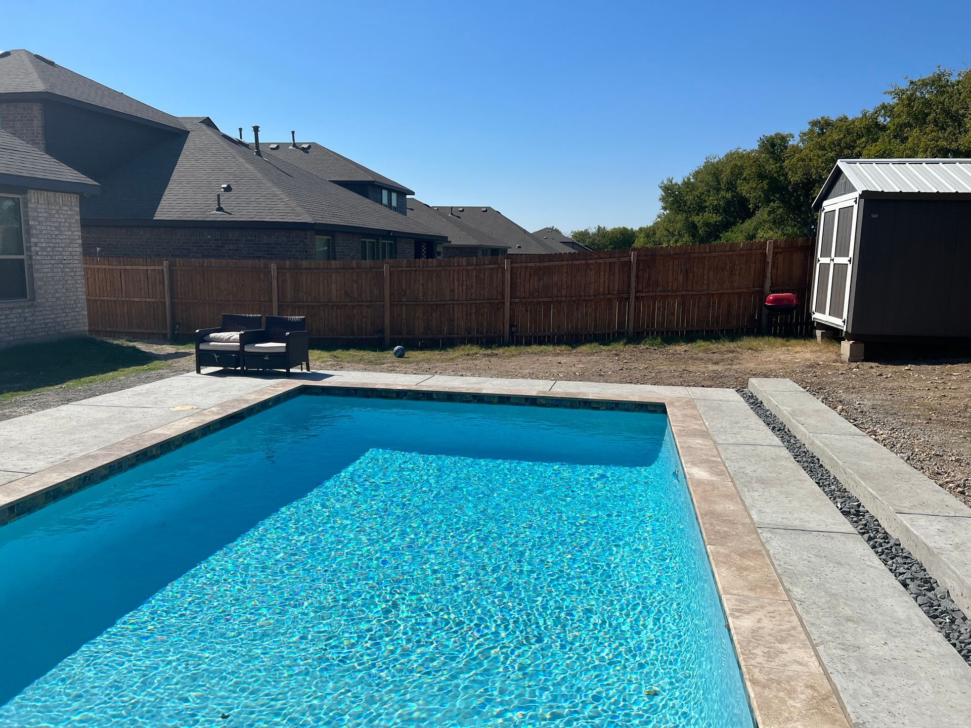 A large swimming pool is in the backyard of a house.