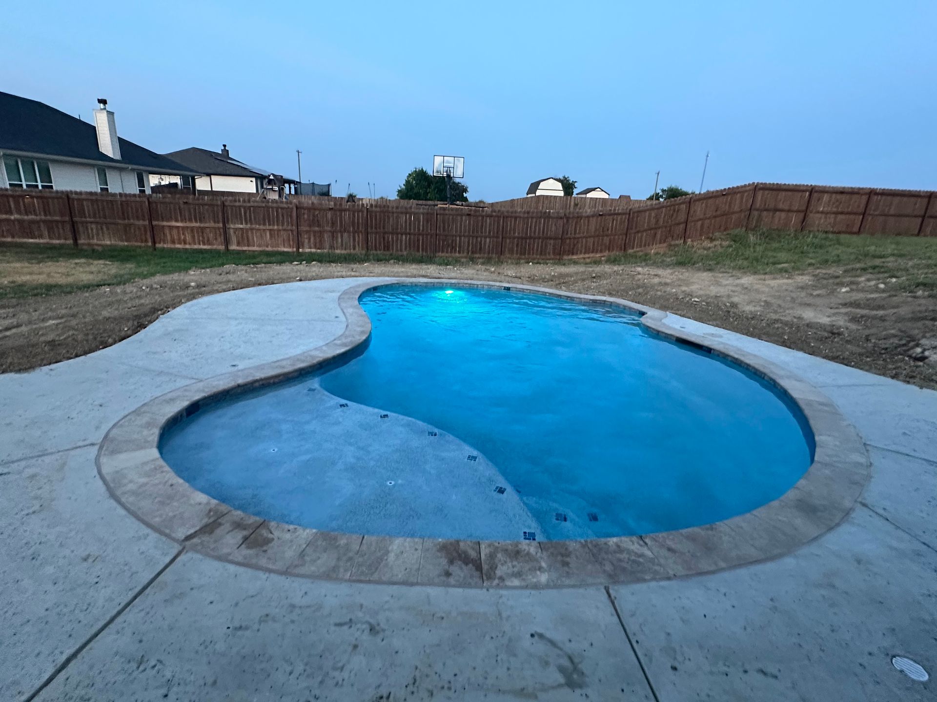 A swimming pool in a backyard with a fence in the background