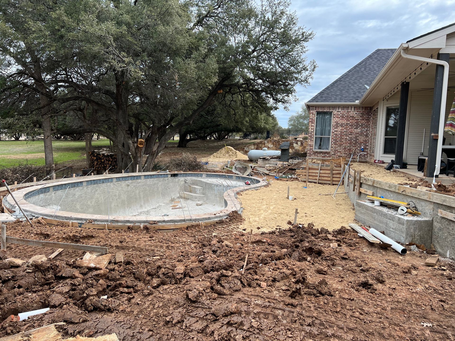 A swimming pool is being built in the backyard of a house.