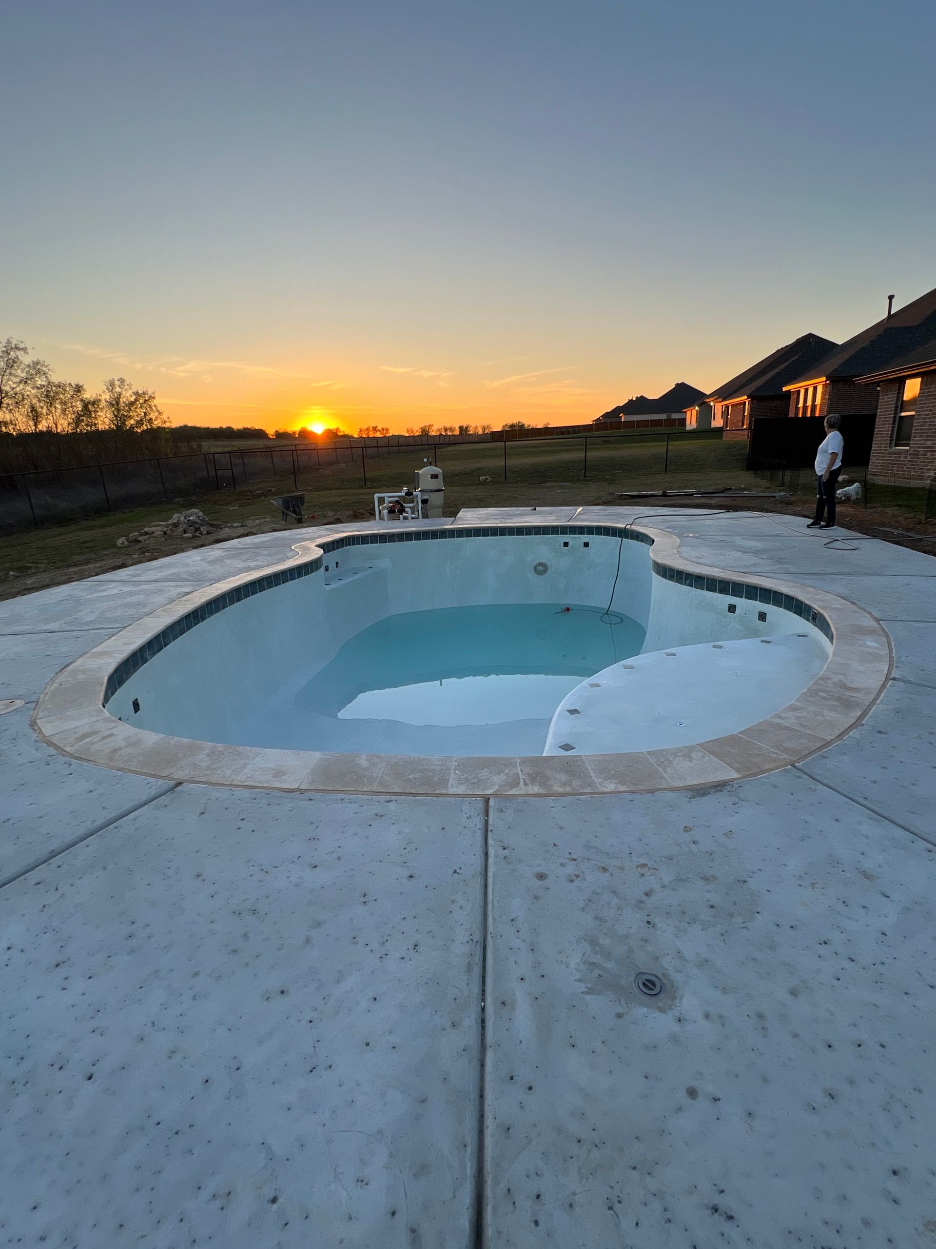 A large swimming pool with a sunset in the background.
