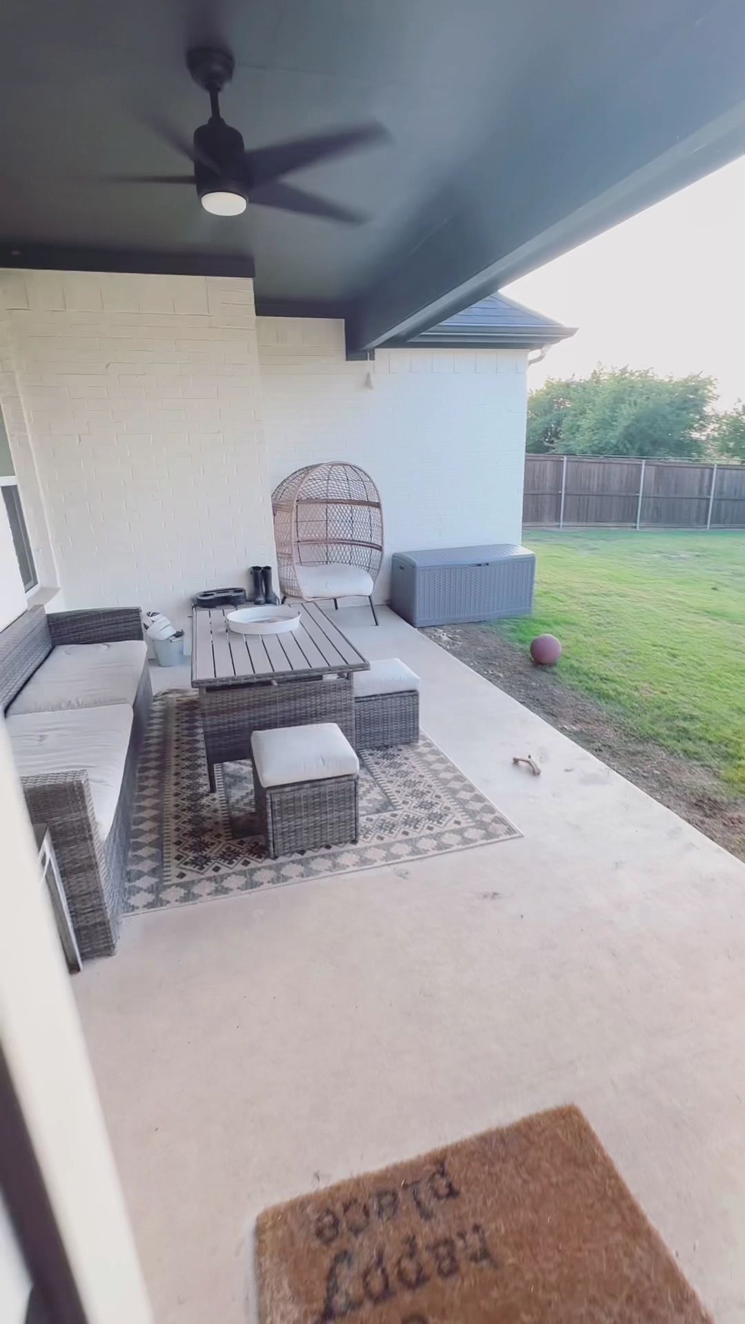 A patio with a ceiling fan and a welcome mat.