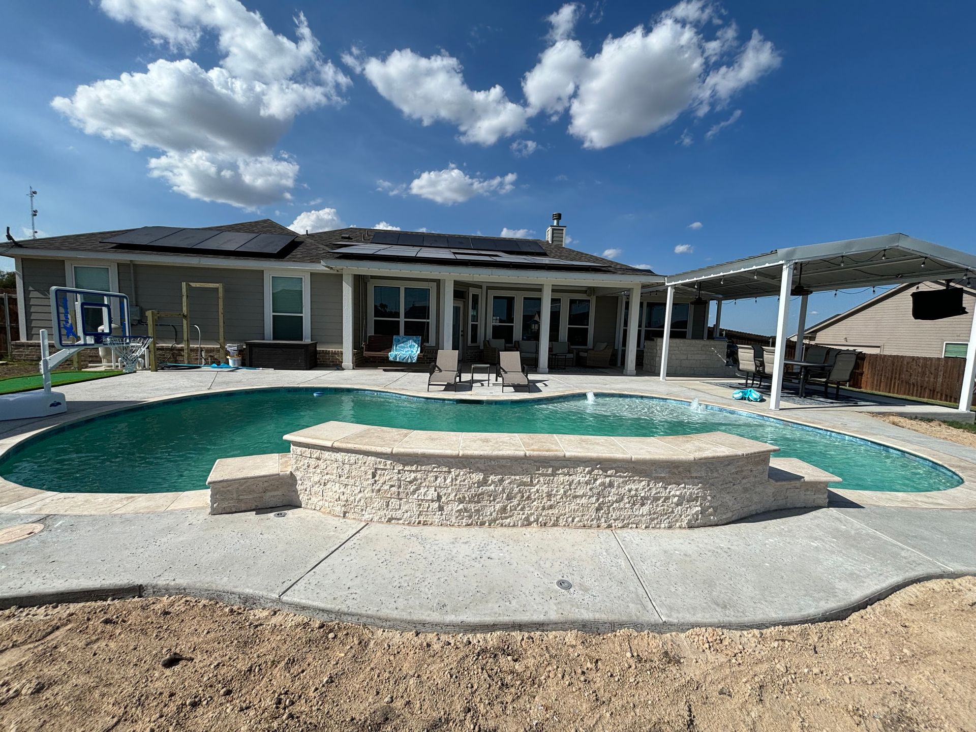A large swimming pool is in the backyard of a house.