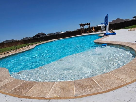 A large swimming pool with a hot tub in the middle of it.