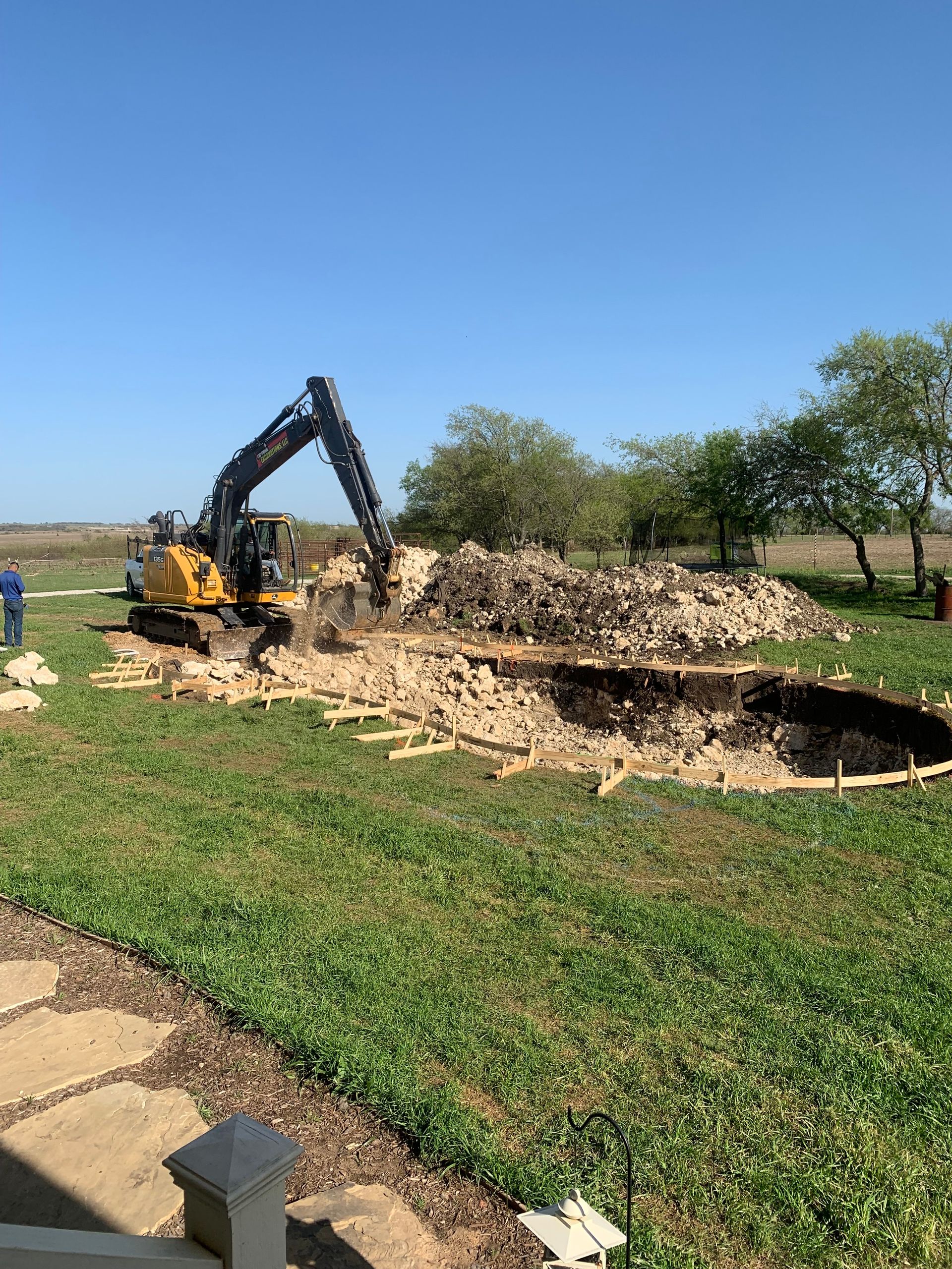 A bulldozer is digging a hole in the ground in a yard.