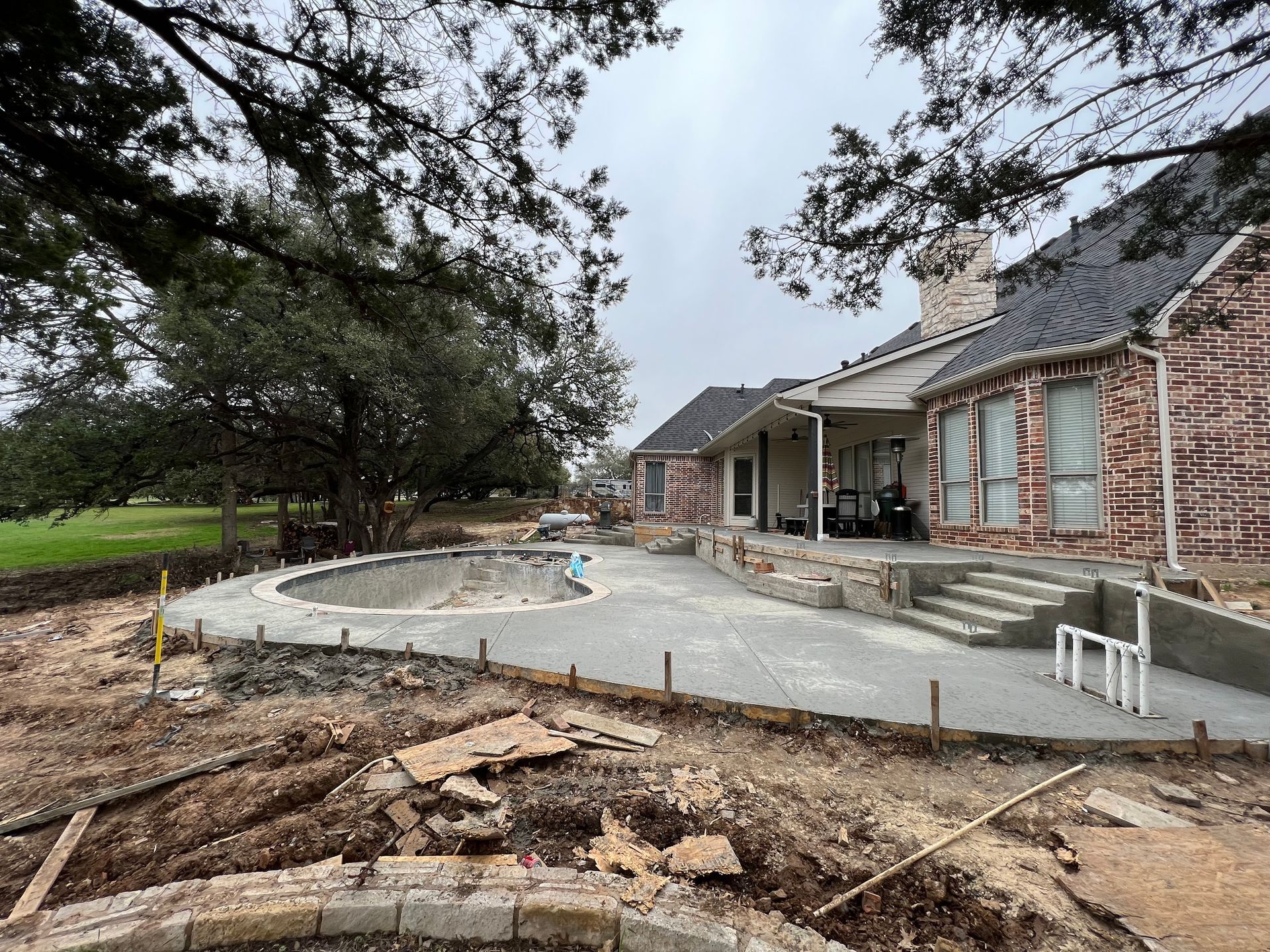 A brick house with a swimming pool in the backyard under construction.
