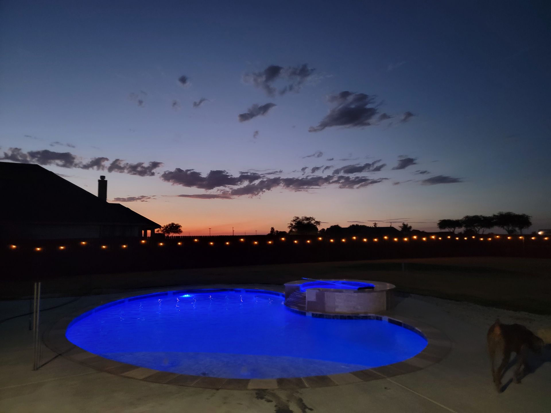 A swimming pool is lit up with blue lights at night