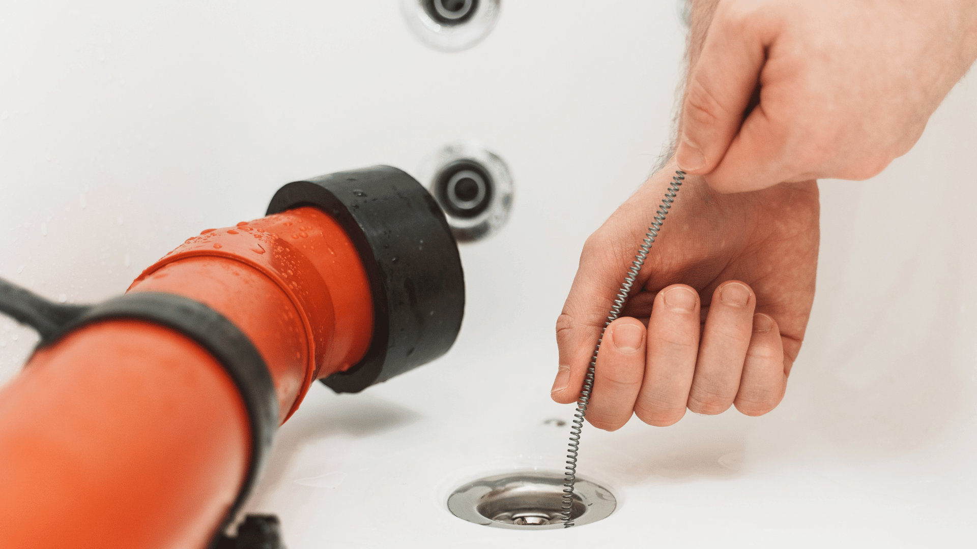 A person is cleaning a drain in a bathtub with a chain.