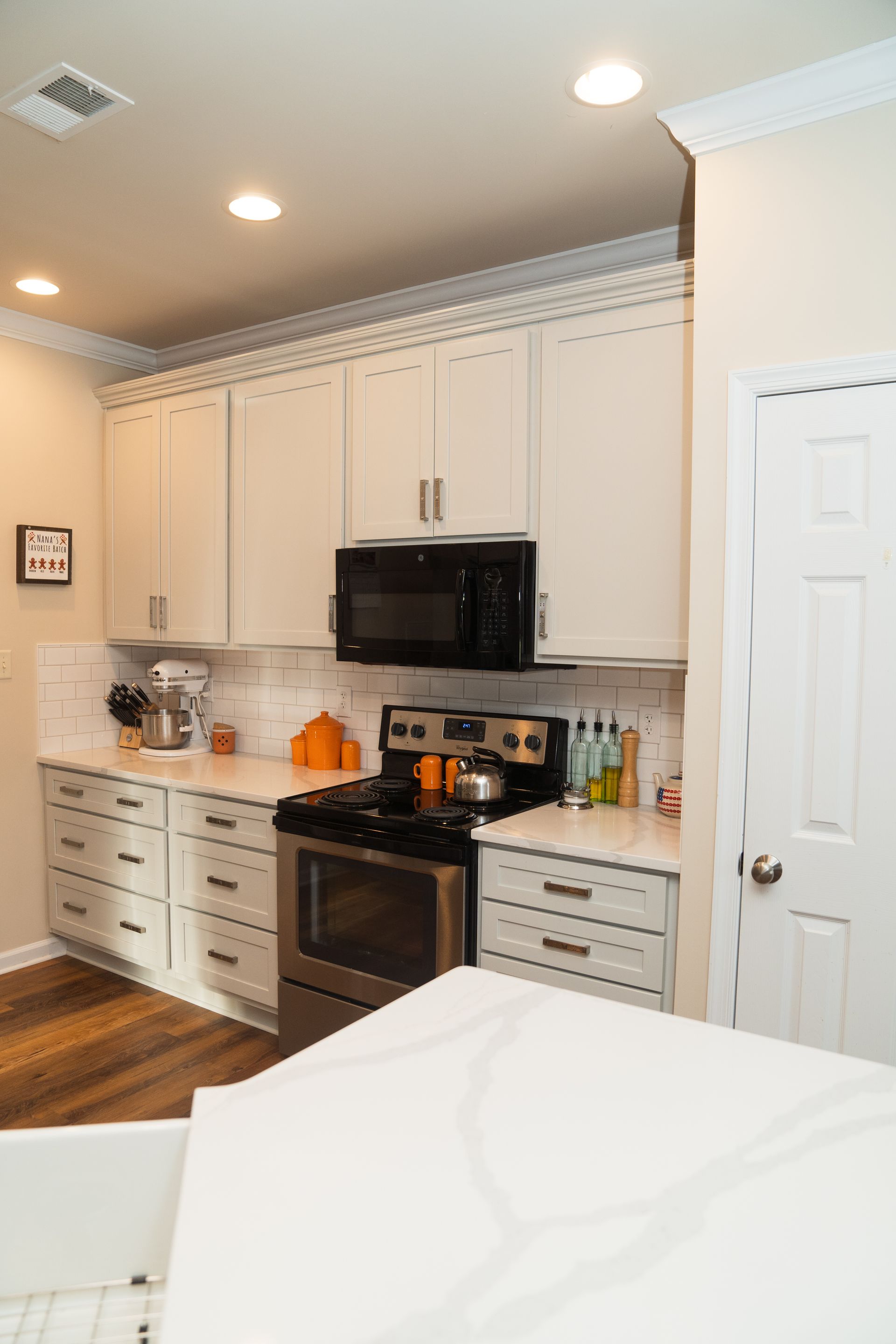A kitchen with white cabinets, a stove, a microwave, and a sink.