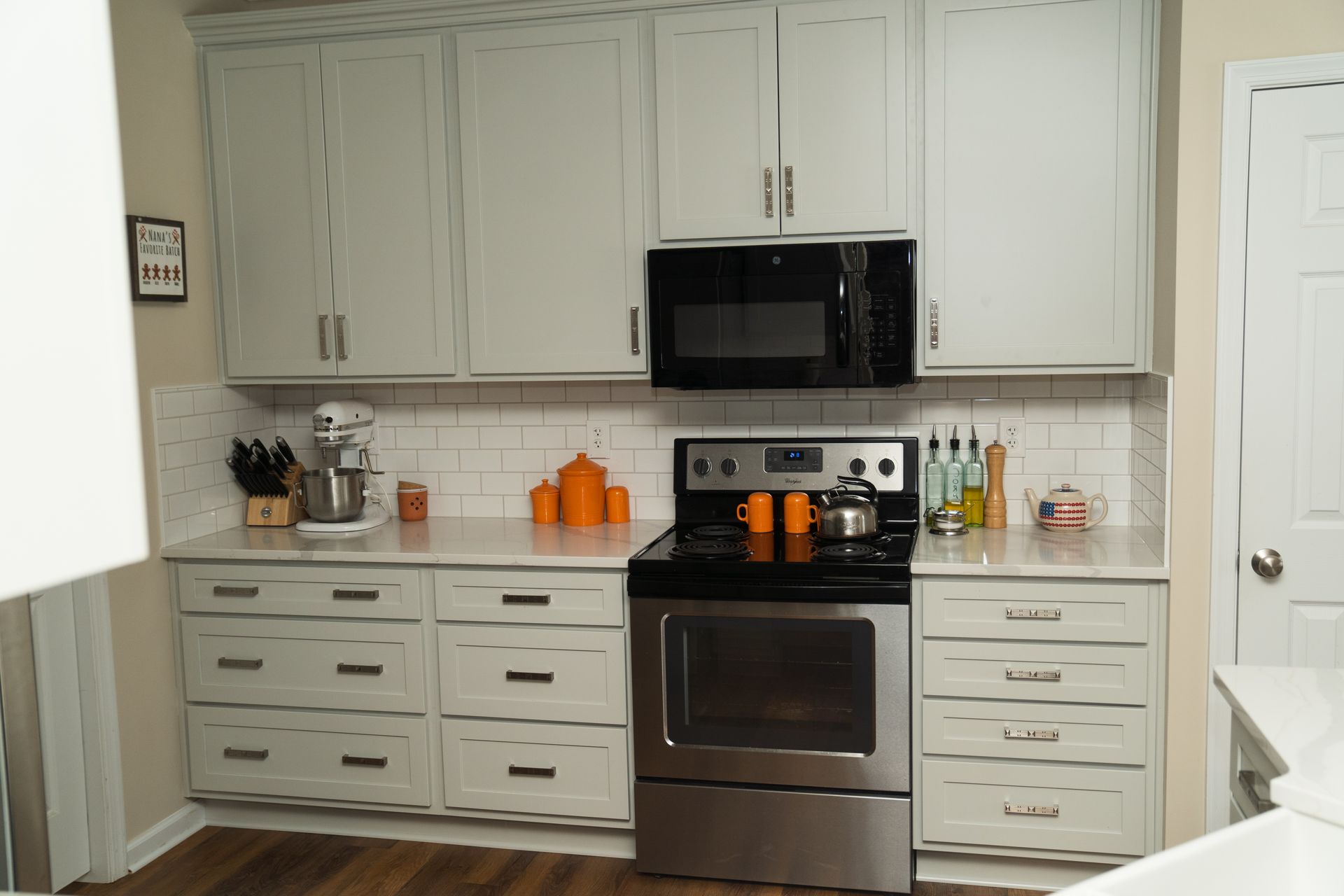 A kitchen with white cabinets, stainless steel appliances, and a microwave.