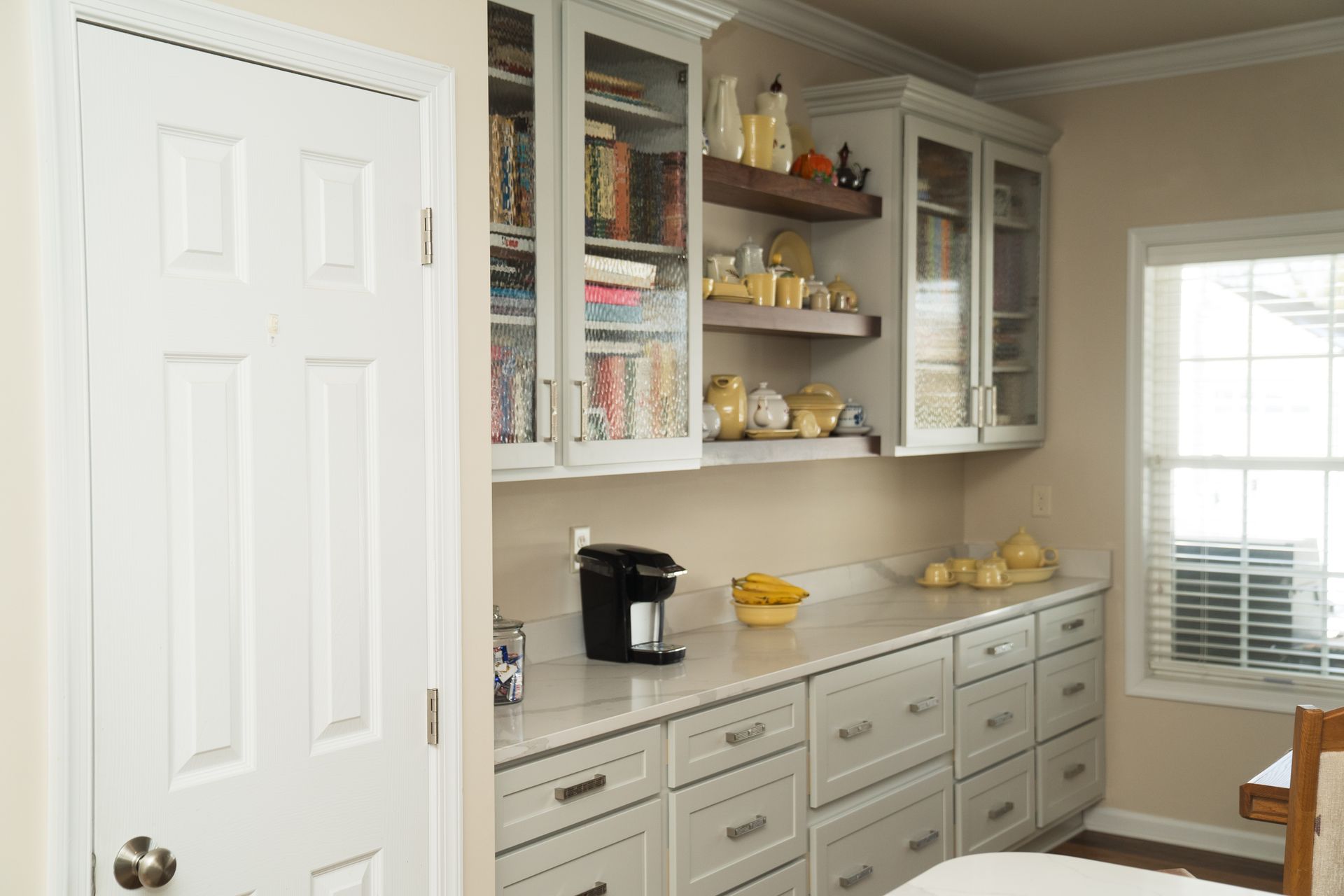 A kitchen with white cabinets and a coffee maker on the counter.