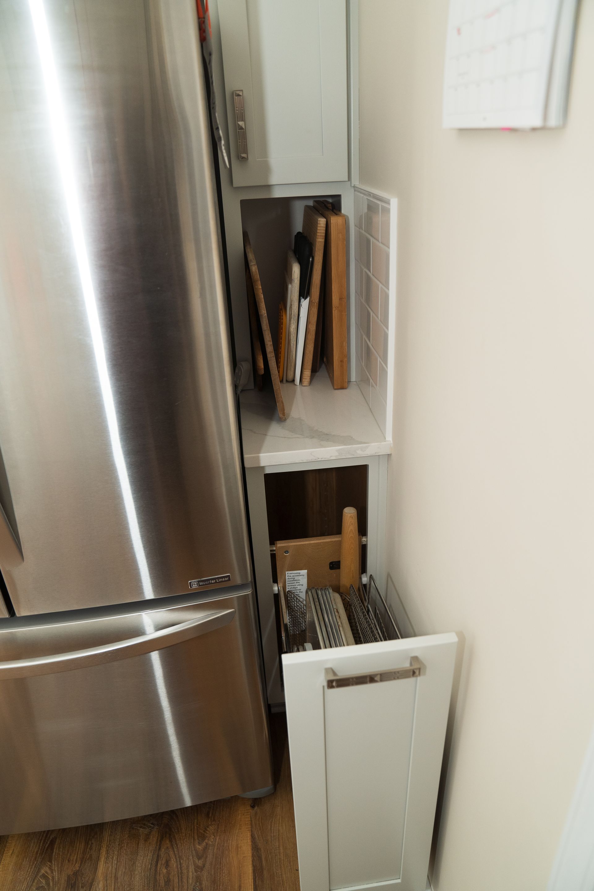 A stainless steel refrigerator is in a kitchen next to a white cabinet.