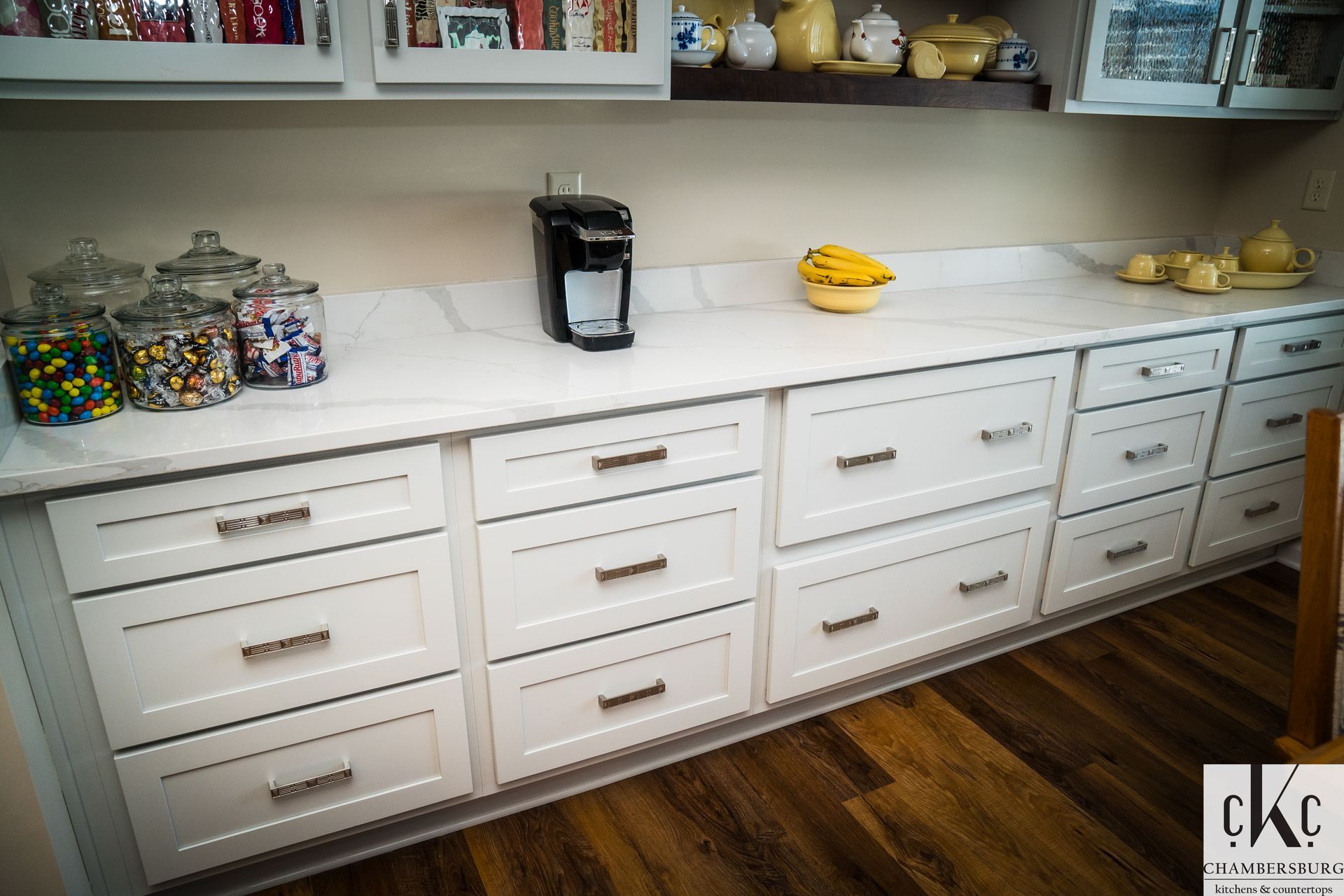A kitchen with white cabinets and a coffee maker on the counter.