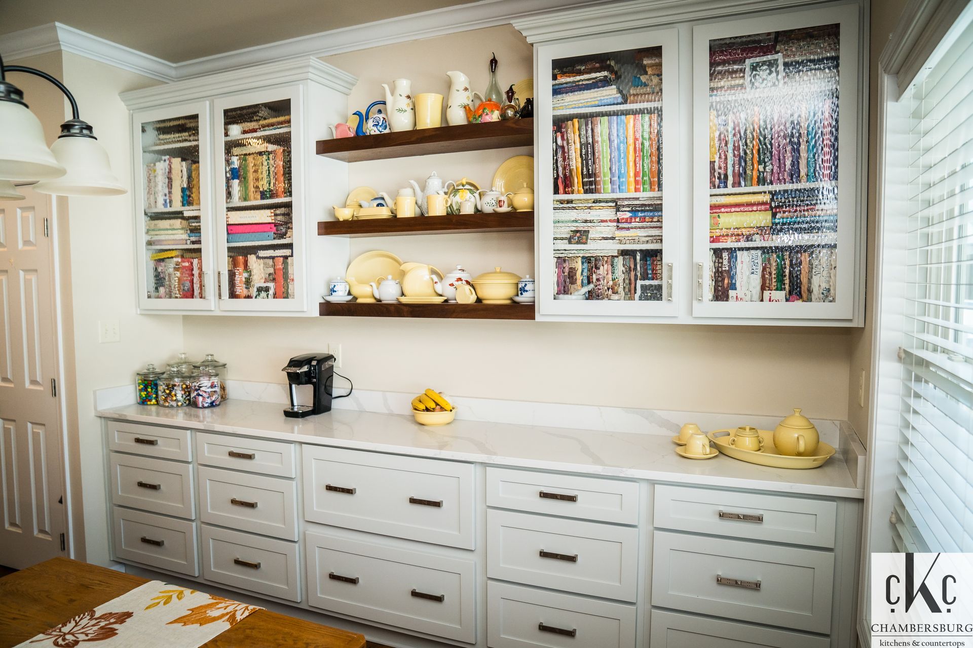 A kitchen with white cabinets, drawers, shelves and a coffee maker.